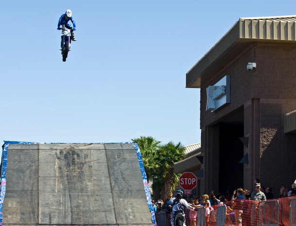 Ted Culbertson jumps his motorcross bike while Keith Slayer high fives crowd members Sept. 8, 2012, at The Exchange here. Red Bull Jams, a motorcross tour designed to give back to troops and their families by performing at military installations, made its fourth stop on its first tour at Nellis Air Force Base. The motorcross riders on this tour were Ted Culbertson, Keith Sayer and Rodney Renner. (U.S. Air Force photo by Senior Airman Jack Sanders)