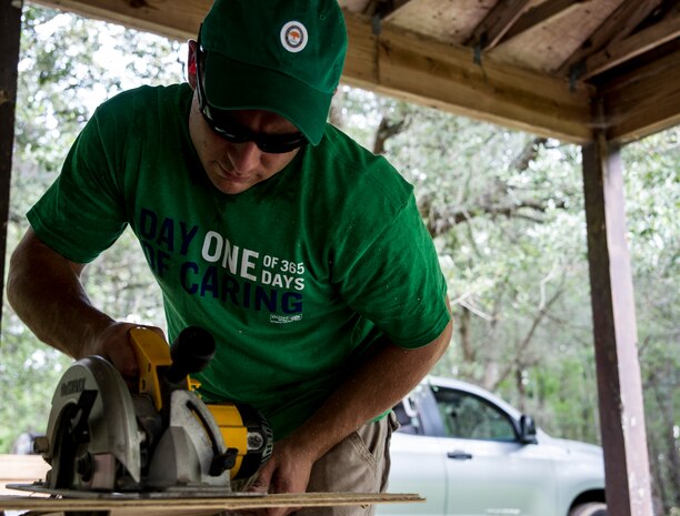 Senior Airman Nathan Pringle, 628th Civil Engineer Squadron emergency manager, uses a saw to cut boards to replace old wood at a camp site at the Girl Scout Plantation on Sept. 7, 2012 in Cordesville, S.C.  Various units of JB Charleston participated in aiding restoration of the facilities on the camp.  The Day of Caring, organized locally by the Trident United Way, saw more than 8,500 volunteers working on more than 300 projects around the Lowcountry.