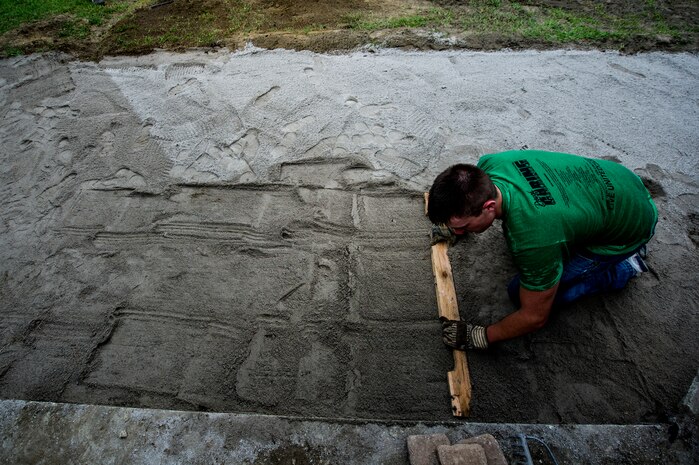 Seaman Matt Castle, Naval Nuclear Power Training Command Machinist’s Mate student, levels out soil to lay walking stones at Marrington Middle School during the Day of Caring Sept. 7, 2012, at Joint Base Charleston - Weapons Station, S.C. The Day of Caring, organized locally by the Trident United Way, saw more than 8,500 volunteers working on more than 300 projects around the Lowcountry. (U.S. Air Force photo/Airman 1st Class George Goslin)
