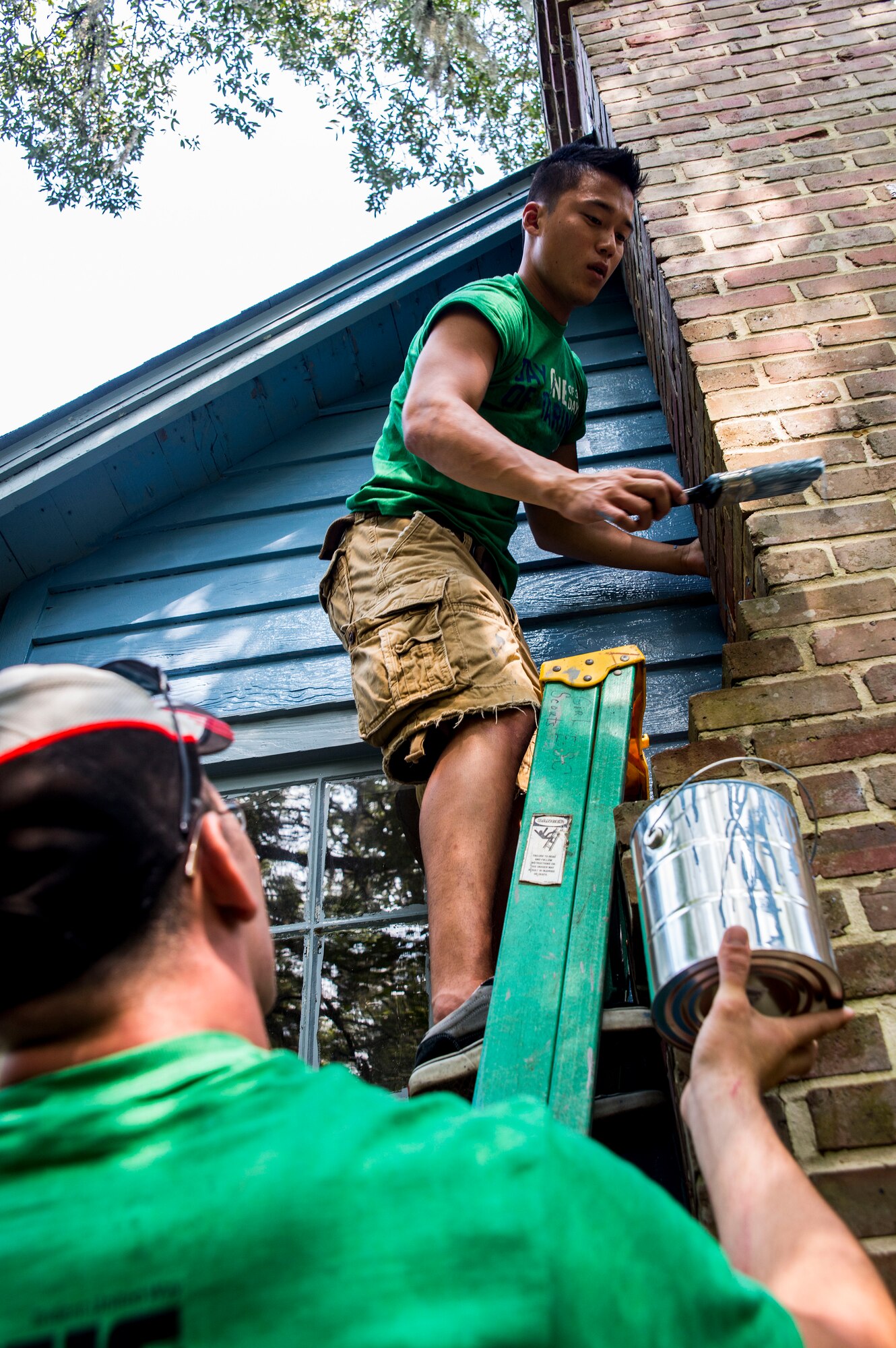 Senior Airman Ju Park and Airmen 1st Class Christopher Widden, 628th Civil Engineer Squadron power productions technicians, paints the side of a house at the Girl Scout Plantation on Sept. 7, 2012 in Cordesville, S.C.  Various units of JB Charleston participated in aiding restoration of facilities on the camp.  The Day of Caring, organized locally by the Trident United Way, saw more than 8,500 volunteers working on more than 300 projects around the Lowcountry.