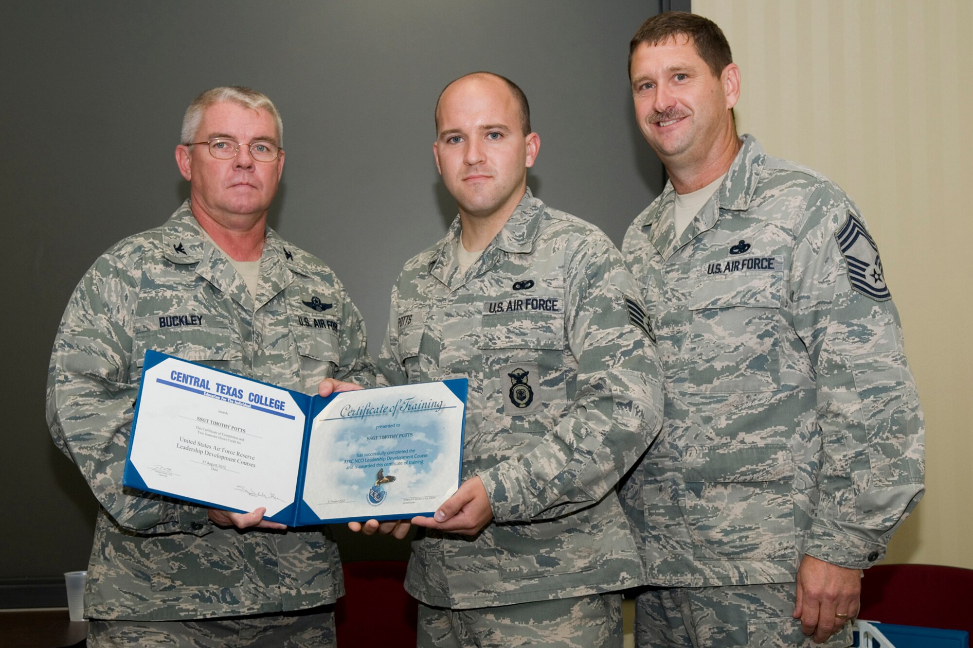 GRISSOM AIR RESERVE BASE, Ind. -- Staff Sgt. Timothy Potts, 434th Security Forces Squadron security response team member, receives a certificate of training from Col. Don Buckley, 434th Air Refueling Wing commander, and Chief Master Sergeant James Burba, 434th Maintenance Operations Flight maintenance superintendent, at a graduation ceremony for a Non-Commissioned Officer Leadership Development Course here Aug. 17. Potts graduated the course with 20 other NCOs. (U.S. Air Force photo/Senior Airman Andrew McLaughlin)