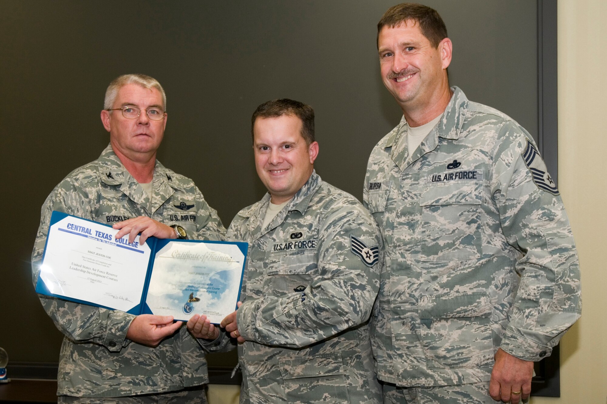 GRISSOM AIR RESERVE BASE, Ind. -- Staff Sgt. Justin Coe, 434th Security Forces Squadron security response team member, receives a certificate of training from Col. Don Buckley, 434th Air Refueling Wing commander, and Chief Master Sergeant James Burba, 434th Maintenance Operations Flight maintenance superintendent, at a graduation ceremony for a Non-Commissioned Officer Leadership Development Course here Aug. 17. Coe graduated the course with 20 other NCOs. (U.S. Air Force photo/Senior Airman Andrew McLaughlin)