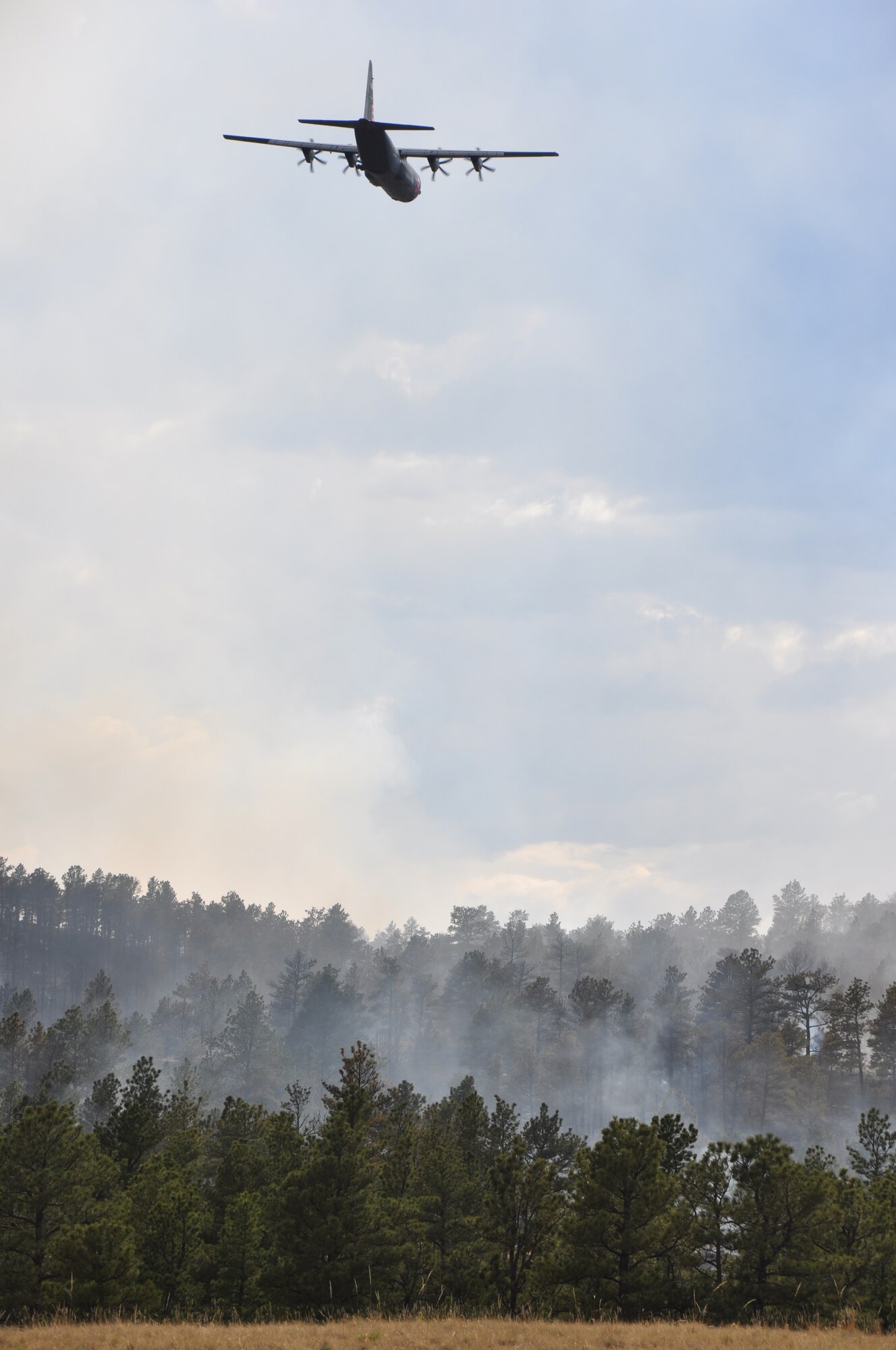 A California Air National Guard C-130, carrying the Modular Airborne Fire Fighting System, flies over smoke and fire from the Sawmill Canyon Fire on the Camp Guernsey Joint Training Center's North Training Area, July 16, 2012. The fire began July 14 and consumed 9.600 acres of timber and grass by July 17. MAFFS is a self-contained aerial firefighting system owned by the U.S. Forest Service that can discharge 3,000 gallons of water or fire retardant in less than five seconds, covering an area one-quarter of a mile long by 100 feet wide. (Wyoming National Guard photo by 1st Lt. Christian Venhuizen)