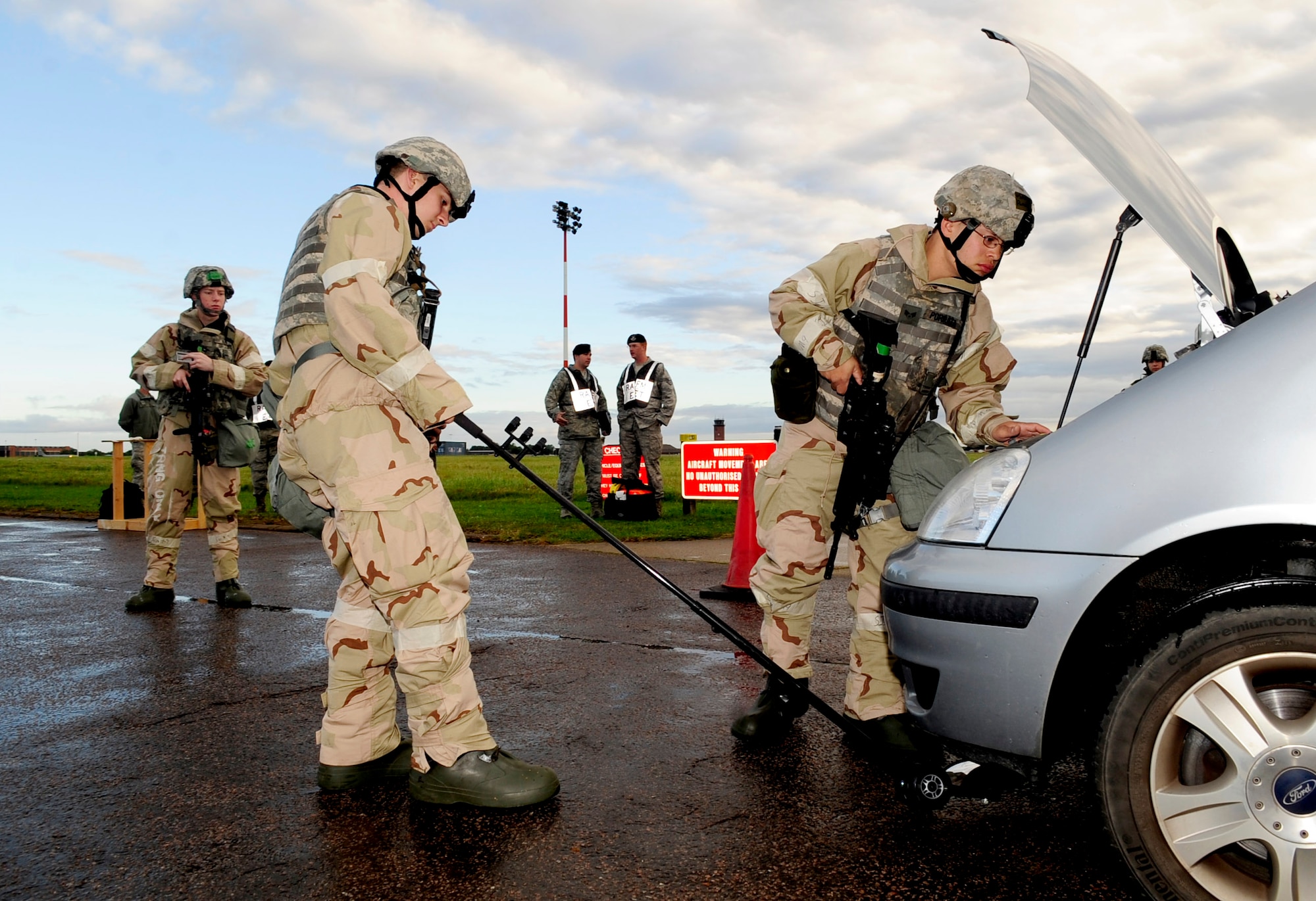 RAF MILDENHALL, England – Airman Nicholas Bates, 100th Security Forces Squadron patrolman, uses a search mirror to search for illegal contraband underneath a vehicle while Senior Airman Nathan Porrata, 100th SFS, searches the engine during an operational readiness exercise Sept. 11, 2012, at RAF Mildenhall. The search was held as part of a simulated entry control point inspection during an ORE. (U.S. Air Force photo/Senior Airman Ethan Morgan)