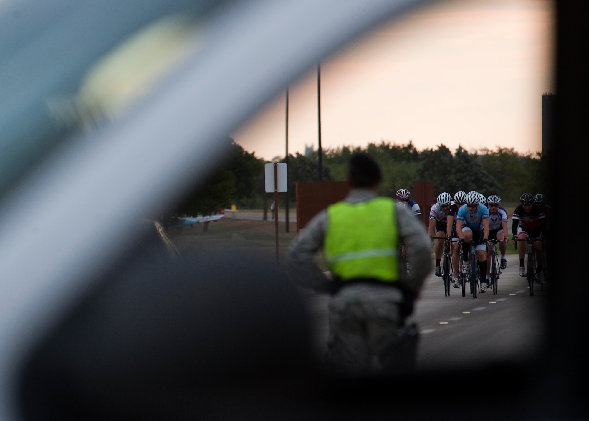 Cyclists ride down Arnold Boulevard while a member of 7th Security Forces Squadron reroutes traffic Sept. 8, 2012, during Le Tour De Dyess at Dyess Air Force Base, Texas. The race began at the fitness center and weaved 26-miles throughout Dyess. (U.S. Air Force photo by Airman 1st Class Damon Kasberg/Released)