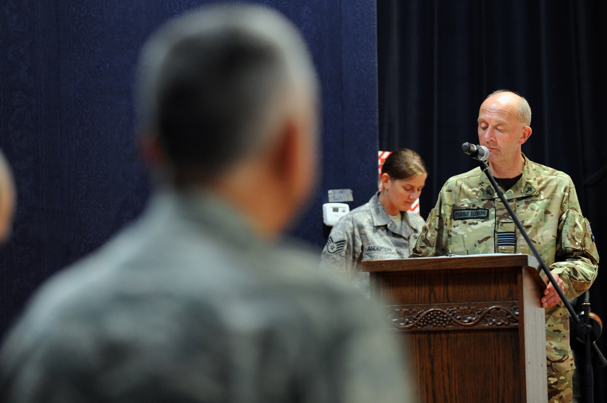 Reverend Wing Commander Padre Nick Heron of the Royal Air Force leads the audience in a moment of silence during the 9/11 Commemoration Ceremony in Southwest Asia, September 11, 2012. The Grand Slam Wing observed the 11th anniversary of the Sept. 11, 2001 attack to honor and remember those who lost their lives at the World Trade Center, the Pentagon, the fields of Shanksville, Penn., and on the battlegrounds of Iraq and Afghanistan. (U.S. Air Force photo/Staff Sgt. Sheila deVera)