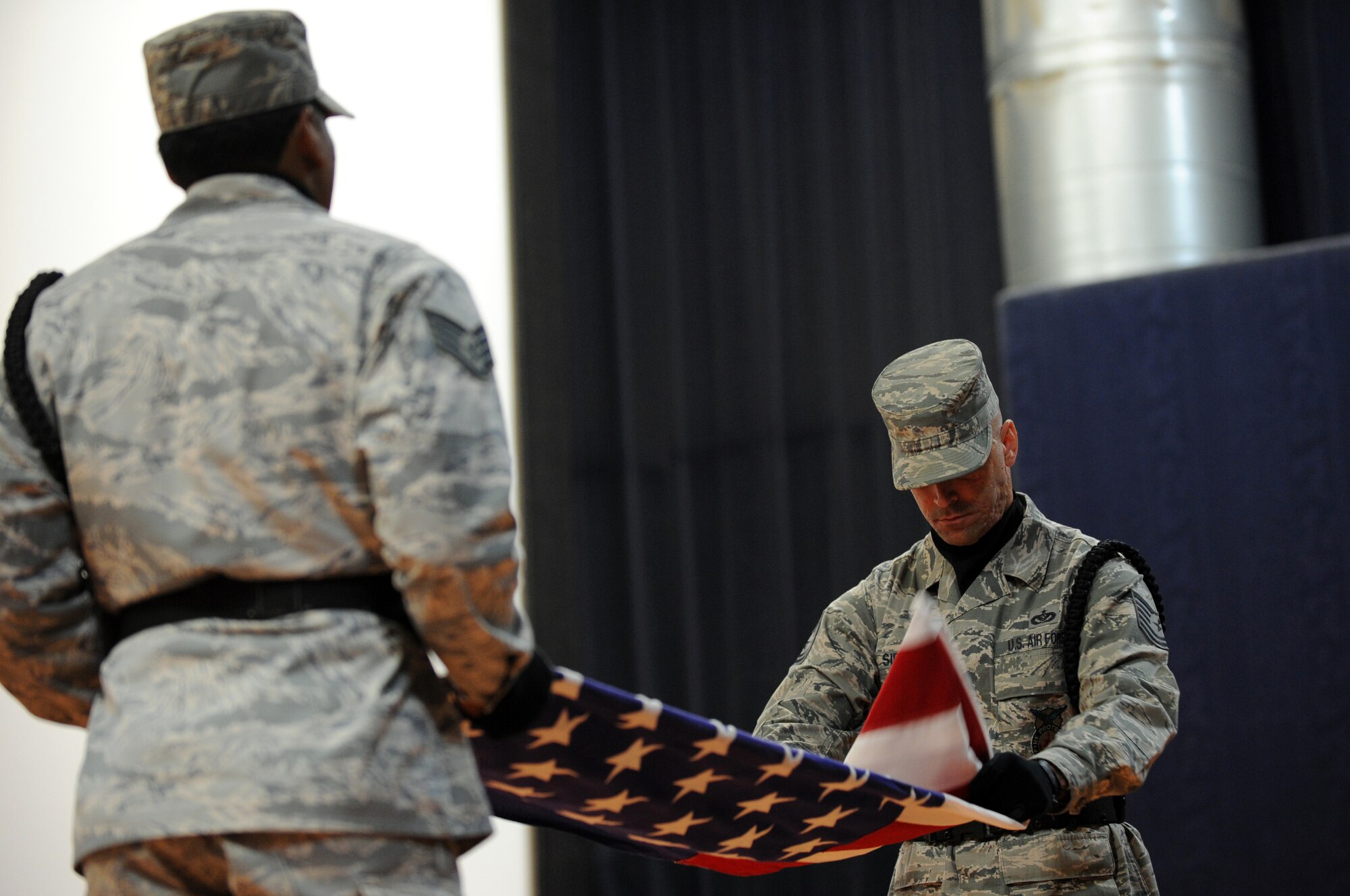379th Air Expeditonary Wing Honor Guard Tech Sgt. Thomas Sidoti (left) and Staff Sgt. Marquis Skinner perform a flag folding during the 9/11 Commemoration Ceremony in Southwest Asia, September 11, 2012. The Grand Slam Wing observed the 11th anniversary of the Sept. 11, 2001 attack to honor and remember those who lost their lives at the World Trade Center, the Pentagon, the fields of Shanksville, Penn., and on the battlegrounds of Iraq and Afghanistan. (U.S. Air Force photo/Staff Sgt. Sheila deVera)