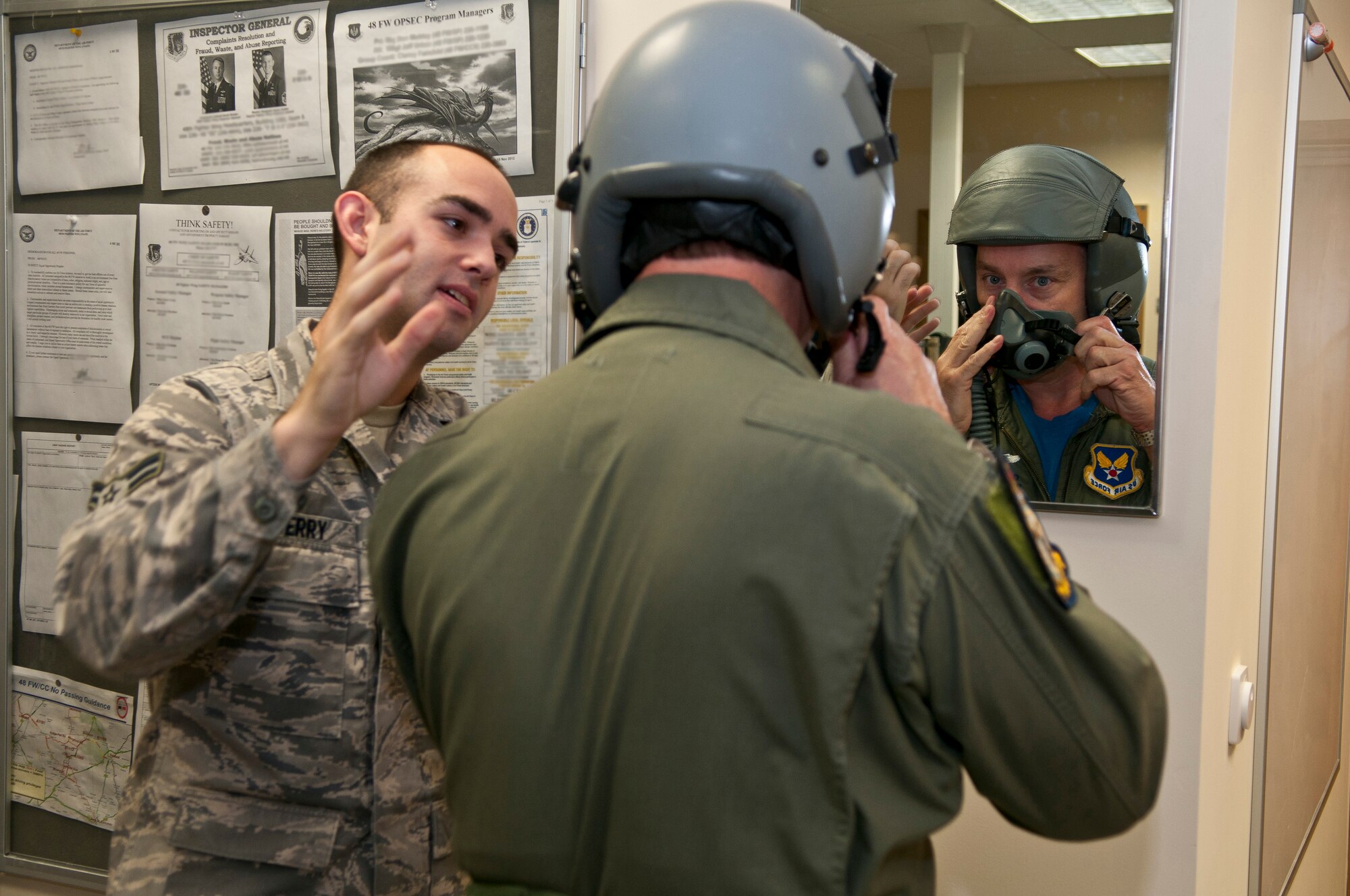ROYAL AIR FORCE LAKENHEATH, England - Airman 1st Class Jeffrey Berry, 493rd Fighter Squadron aircrew flight equipment apprentice, instructs Colin Wills, former 493rd FS honorary commander, how to put on a HGU-55/P flyer’s helmet before his incentive flight Sept. 7, 2012. Wills received an incentive flight with the 493rd FS to better understand the capabilities of the F-15 and to thank him for his service as the squadron’s honorary commander. (U.S. Air Force photo by Senior Airman Connor Estes)