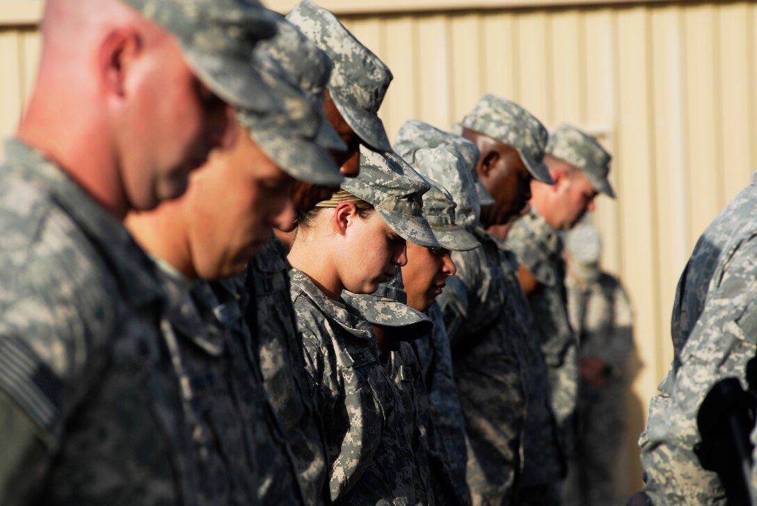 Soldiers deployed to Kandahar Airfield, Afghanistan, Sept. 11, 2012, bow their heads in prayer during a ceremony to commemorate the 9/11 terrorist attacks.