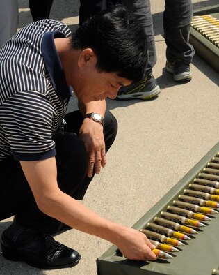 A member of the South Korean media examines a round of ammunition, Sept. 7, 2012, that will be loaded into an F-16 Fighting Falcon at Kunsan Air Base, Republic of Korea. The media was shown the different capabilities of the F-16 and why it is vital to accomplishing the mission on the base. (U.S. Air Force photo/Senior Airman Marcus Morris)