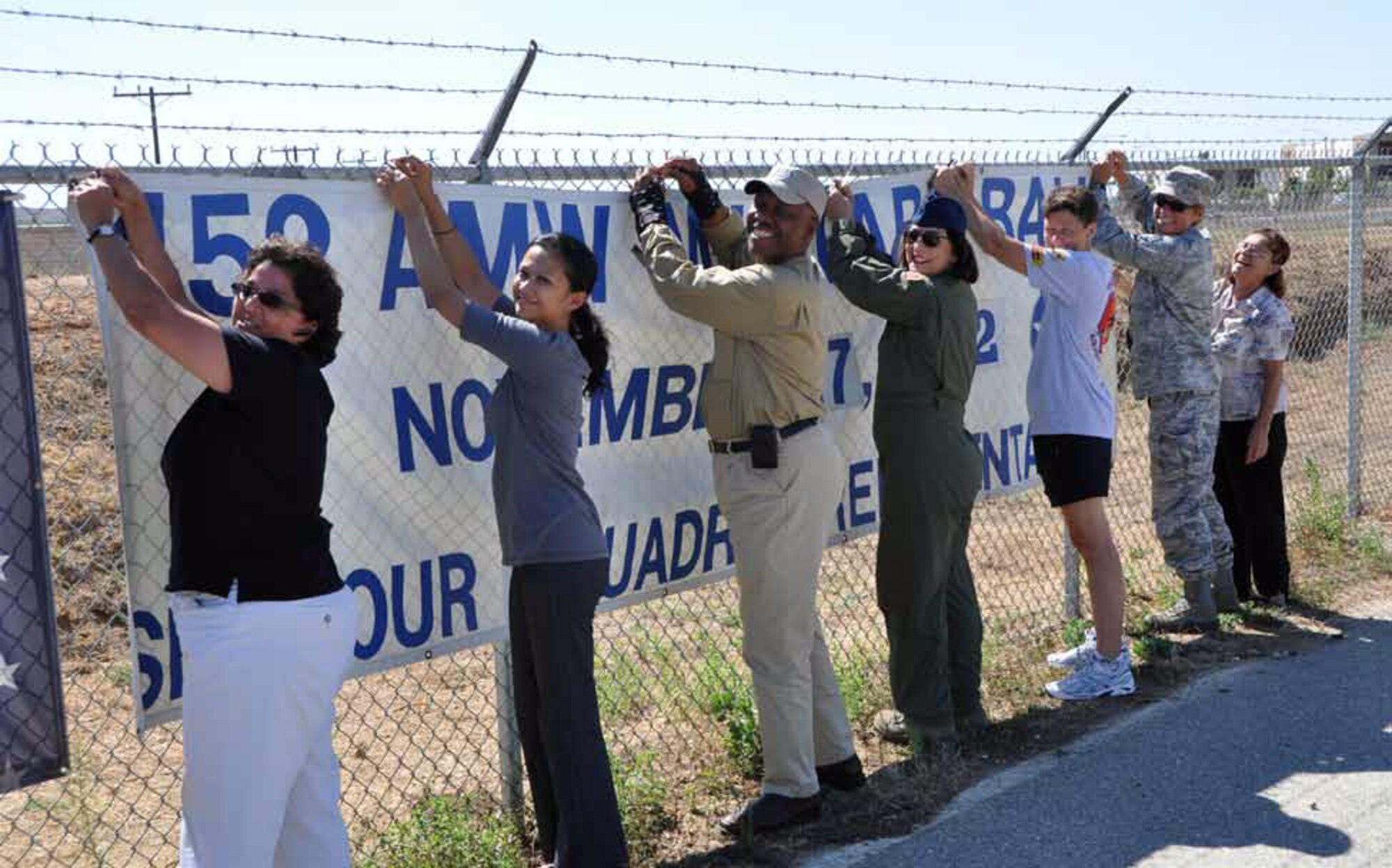 Members of the March Military Ball committee hang their banner on the perimeter fence facing the entrance of March Air Reserve Base. The hanging of the banner, kicks-off ticket sales for the 452d AMW Military Ball, which will be held Nov. 17. The 452d AMW Military Ball committee members pictured from left to right: Chief Master Sgt. Sylvia Frausto, 452nd Force Support Squadron, Master Sgt. Carolyn Erfe, 4th Combat Camera Squadron, Kirby Love, 4th CTCS, Senior Master Sgt. Josephine
Carrillo, 452nd Aeromedical Squadron, Tech. Sgt. Mary Johanson, 4th CTCS, Chief Master Sgt. Karen Krause, 452nd Maintenance Operations Squadron and Elaine Plein, 452nd Air Mobility Wing. (U.S. Air Force photo by Darnell Gardner)
