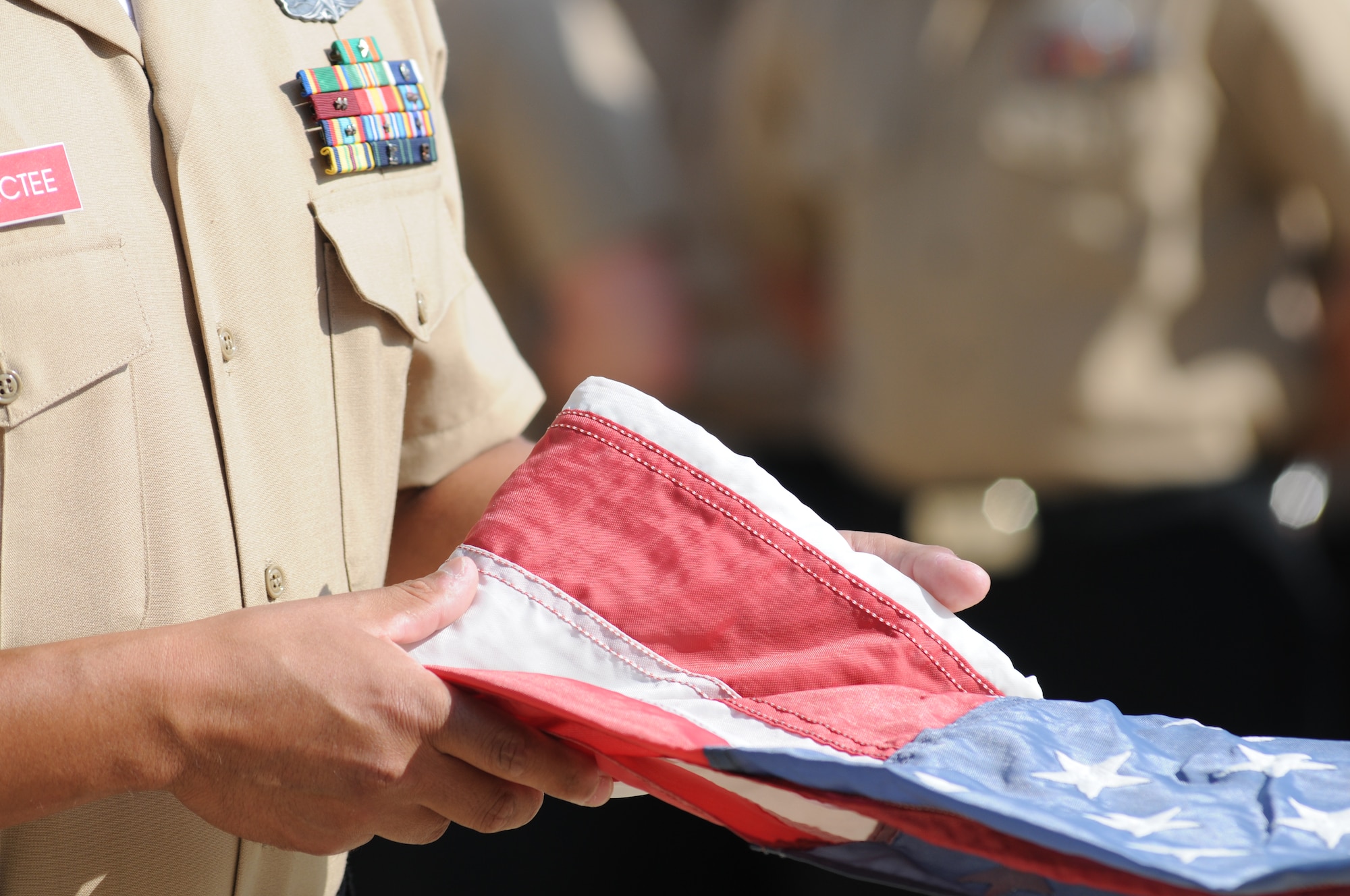 Chief Petty Officer selectee Santiago Jaramillo, Center for Naval Aviation Technical Training Unit Keesler, unfolds a U.S. Flag during a Sept. 11, 2012, ceremony at Keesler Air Force Base, Miss., to honor those who have given their lives since 9/11.  (U.S. Air Force photo by Kemberly Groue)