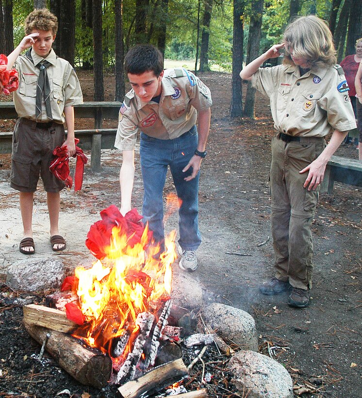 Tyler Muchmeyer and Kevin Peets salute as William Green tosses red stripes from a retiring flag onto a fire.  Scouts from Troop and Pack 220 located on Robins AFB honored the remembrance of the eleventh anniversary of 9/11 with a solemn flag retirement ceremony at the Fire Ring near the Pave Paws facility. (U. S. Air Force photo/Sue Sapp)