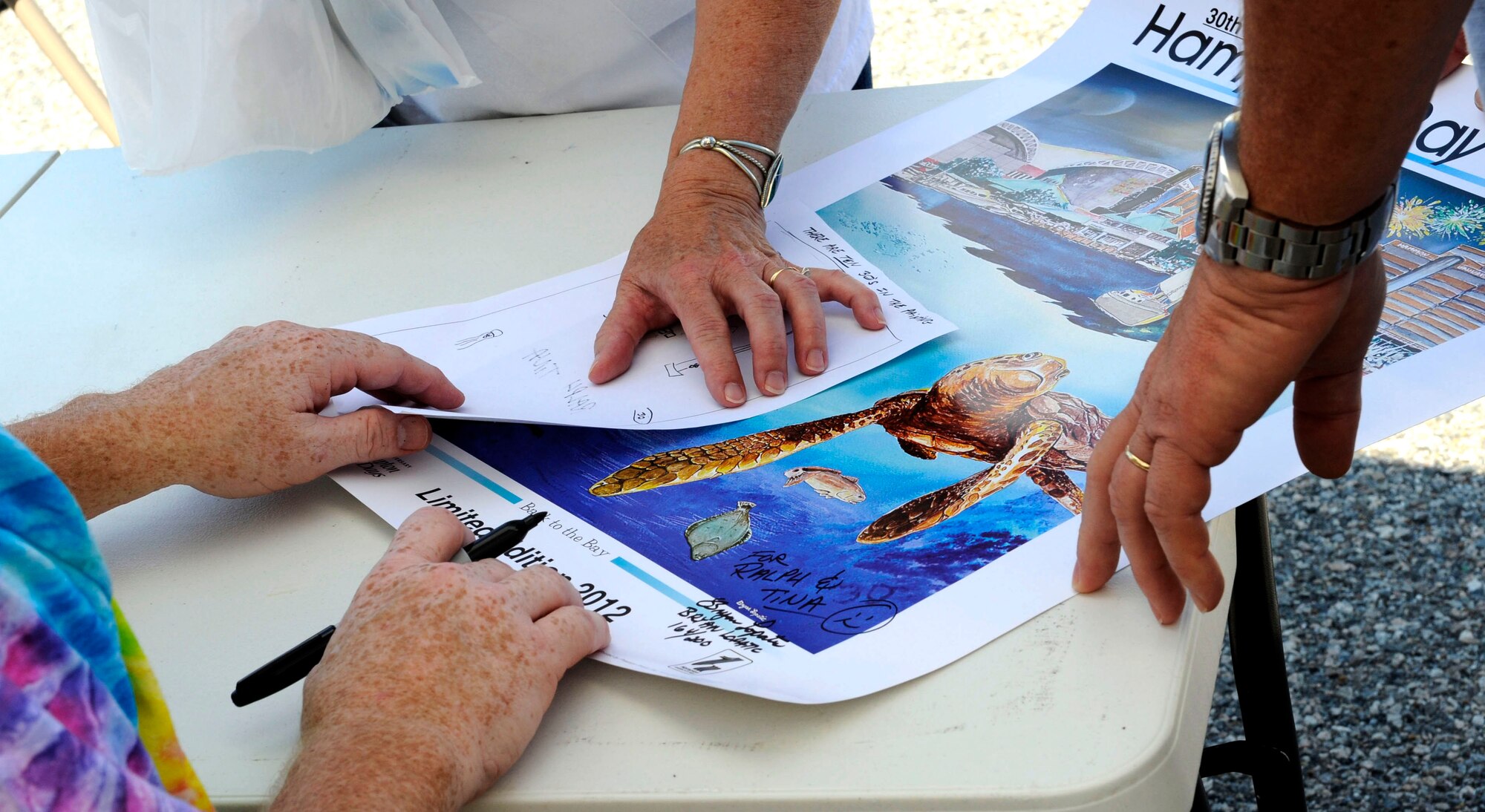 Bryan Lopatic, a U.S. Air Force supervisory illustrator and Air Combat Command Multimedia Center section chief, reveals to festival patrons 10 hidden “30s” placed within his winning poster design, at the 30th Hampton Bay Days festival in Hampton, Va., Sept. 8, 2012. Lopatic placed the number within the poster design to commemorate the festival’s anniversary, which began in 1982. (U.S. Air Force photo by Staff Sgt. Krystie Martinez/Released)