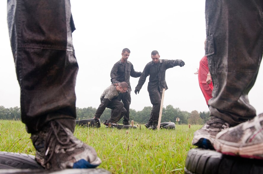 HANSCOM AIR FORCE BASE, Mass. – Senior Airman Matthew Stranz (left) works with his teammates to move across a field using tires during a Warrior Day obstacle Aug. 6. Teams competed in the monthly warrior event that invited other branches of the armed forces to compete. (U.S. Air Force photo by Mark Wyatt)  