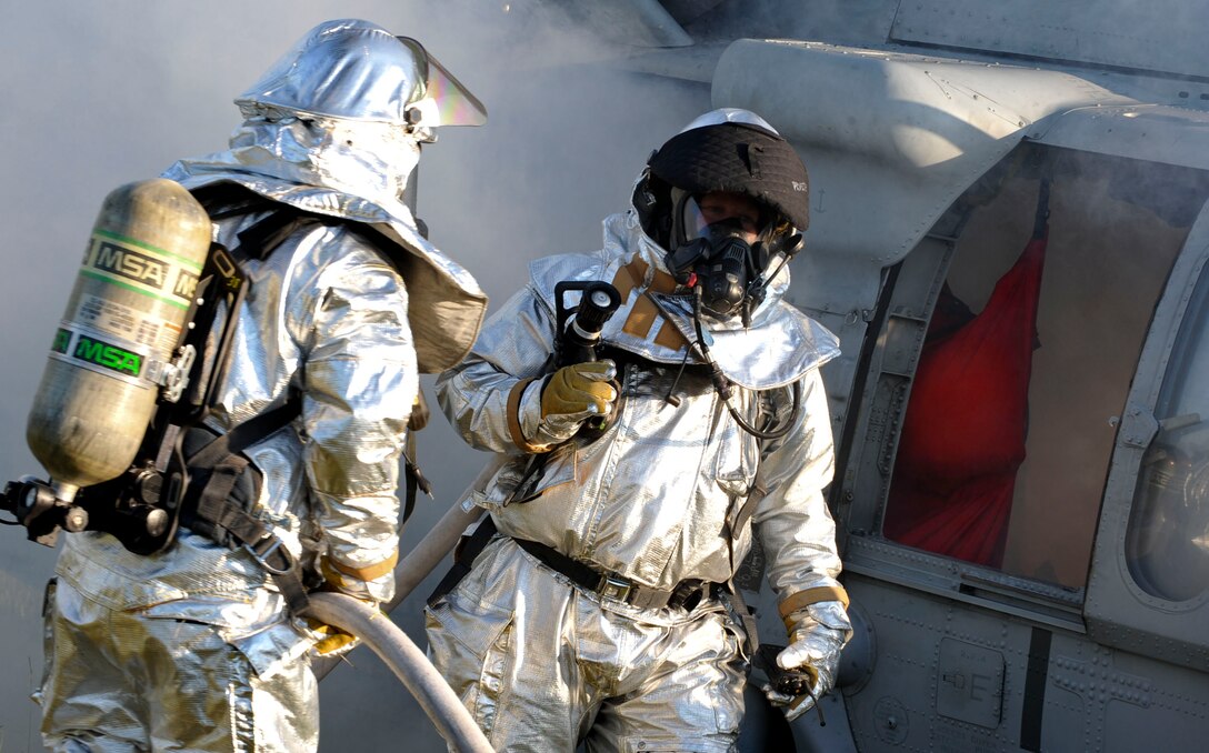 Firefighters with the 733rd Civil Engineer Division fire department pull their hose from a UH-60 Blackhawk Helicopter after extinguishing the pretend fire during a major accident response exercise at Fort Eustis, Va., Sept. 12, 2012. The MARE was the first rotary-wing crash exercise performed by the 633rd Air Base Wing at Fort Eustis since becoming a joint base in 2010. (U.S. Air Force photo by Staff Sgt. Wesley Farnsworth / Released)