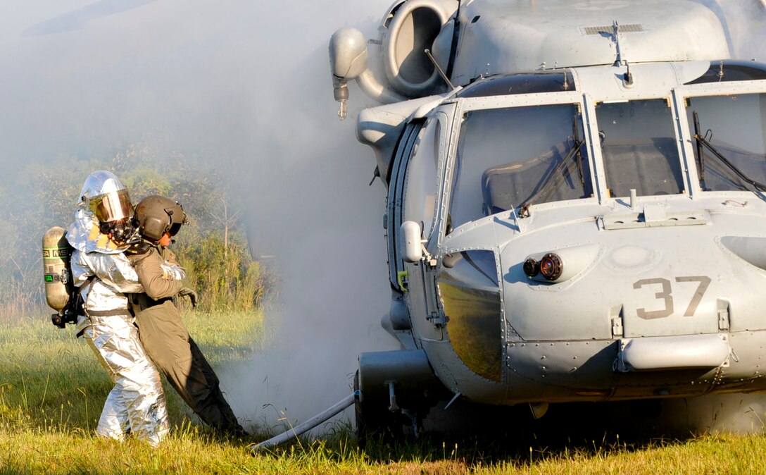 A Firefighter with the 733rd Civil Engineer Division fire department pulls U.S. Army Sergeant 1st Class Robert Browder, crash victim, to safety from a simulated-downed U.S. NAVY UH-60 Blackhawk helicopter during a major accident response exercise at Fort Eustis, Va., Sept. 12, 2012. First responders are responsible for securing the scene, locating and treating victims and ensuring the fire is put out. (U.S. Air Force photo by Staff Sgt. Wesley Farnsworth / Released)