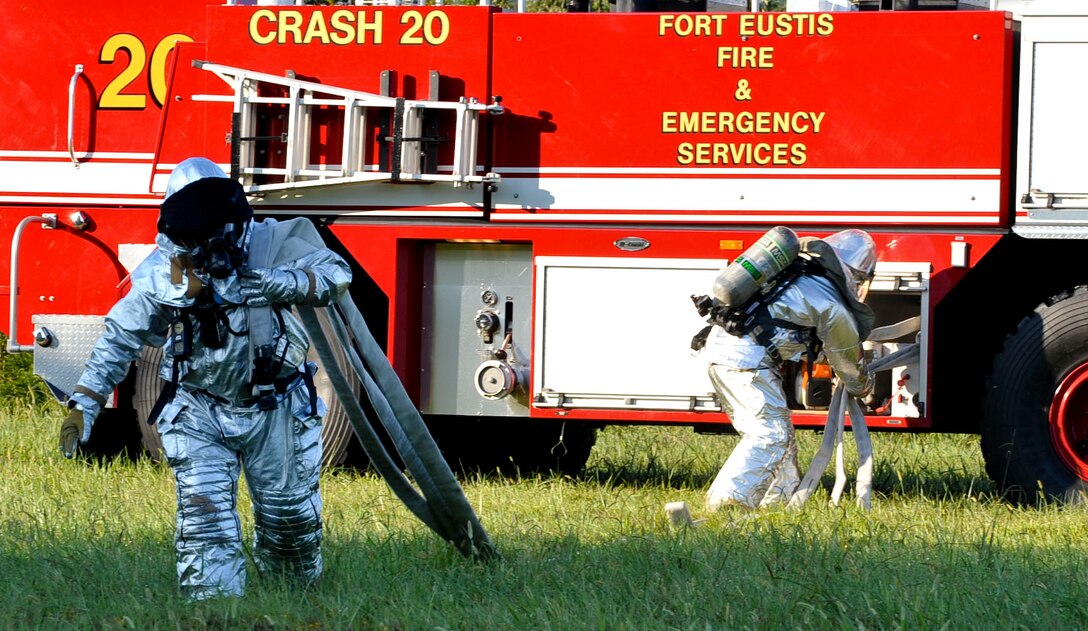 Firefighters with the 733rd Civil Engineer Division fire department pull their hose from the truck at the scene of a downed helicopter during a major accident response exercise at Fort Eustis, Va., Sept. 12, 2012. First responders are responsible for securing the scene, locating and treating victims and ensuring the fire is put out. (U.S. Air Force photo by Staff Sgt. Wesley Farnsworth / Released)