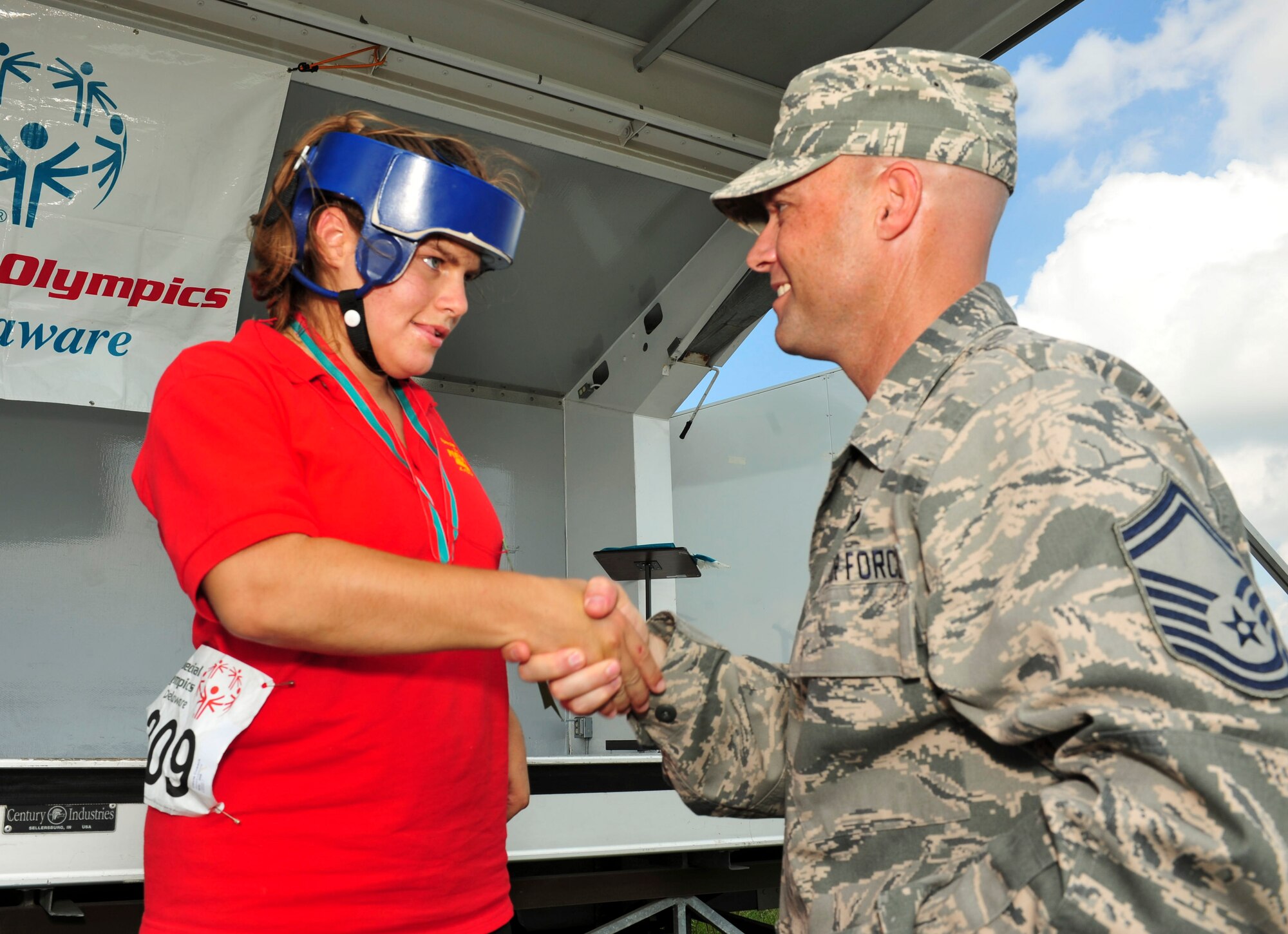 Olivia Cusack receives a participant award from Senior Master Sgt. Daniel Spain during the Delaware Special Olympic cycling event award ceremony at Dover Air Force Base, Del. More than 120 volunteers donated their time to help 42 participants compete in the event.  (U.S. Air Force photo by Master Sgt. Jeanette Spain)