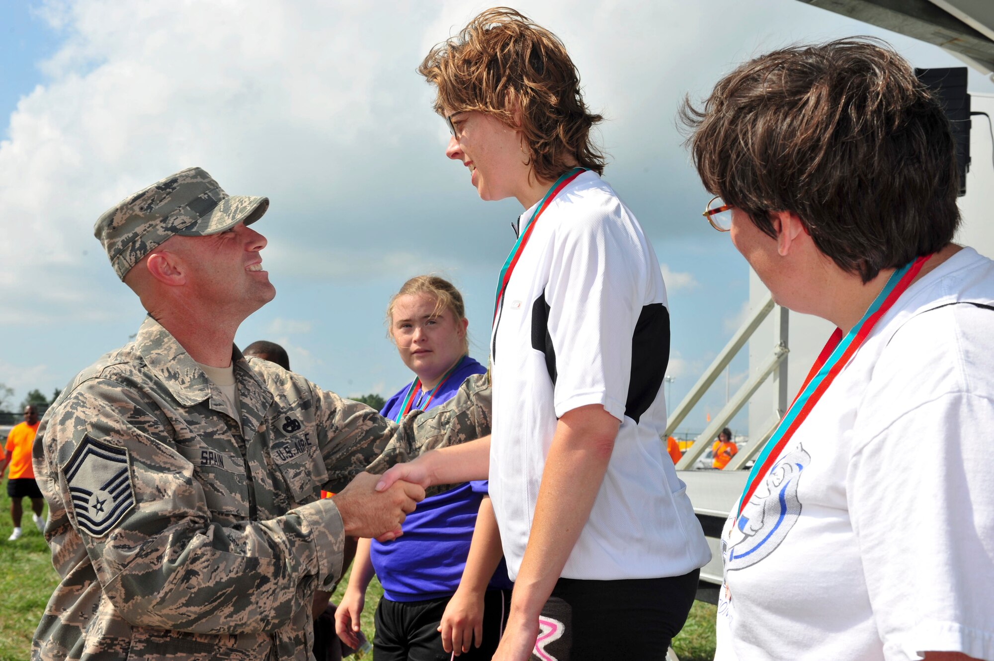 Senior Master Sgt. Daniel Spain presented the gold medal to Renee Kalokitis (center) after winning first place in the 10K race during the Delaware Special Olympic cycling event award ceremony at Dover Air Force Base, Del. Elizabeth Nolan (left) earned second place and Debbie McDaniel (right) garnered third place. More than 120 volunteers donated their time to help 42 participants compete in the event.  (U.S. Air Force photo by Master Sgt. Jeanette Spain)