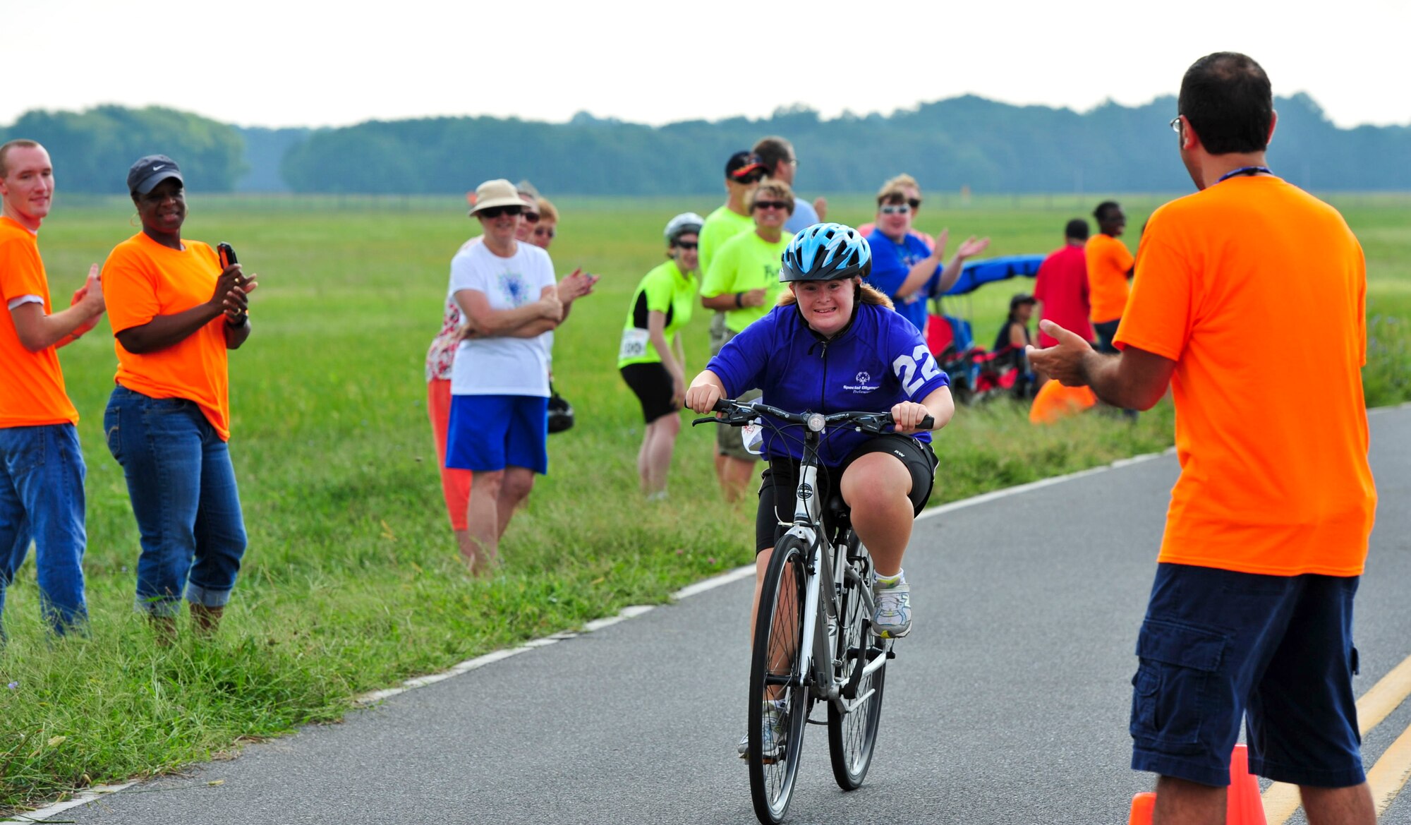 A crowd of volunteers and family members cheer for Elizabeth Nolan (center) as she completes the 10K race during the Delaware Special Olympic cycling event at Dover Air Force Base, Del. More than 120 volunteers donated their time to help 42 participants compete in the event.  (U.S. Air Force photo by Master Sgt. Jeanette Spain)