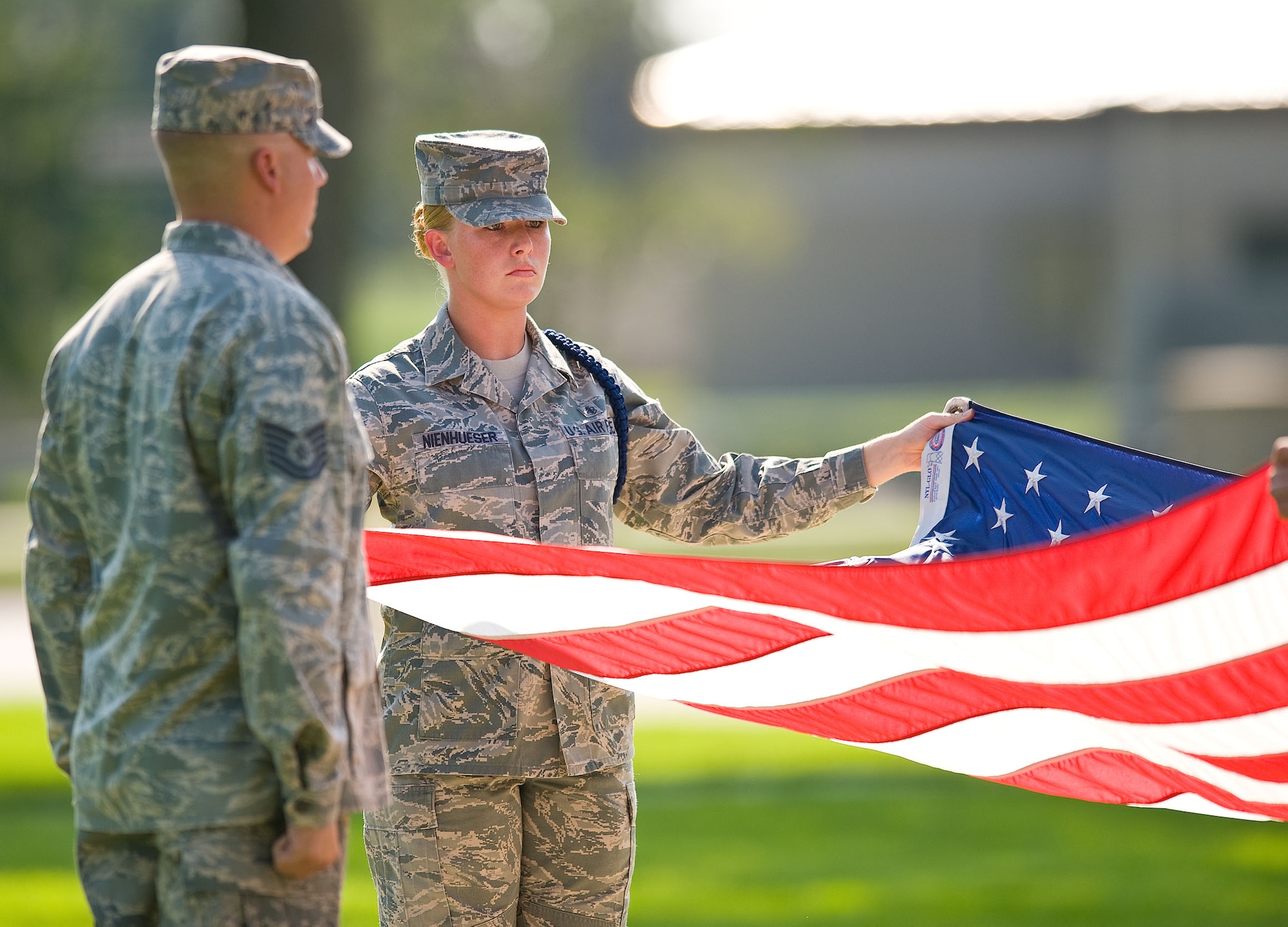 Staff Sgt. Jessica Nienhueser, right, a military training leader assigned to Detachment 3, 373rd Training Squadron, Dover Air Force Base, Del., prepares the American flag for folding during a retreat ceremony at the base flag pole Sept. 7, 2012, at Dover AFB. (U.S. Air Force photo by Roland Balik)
