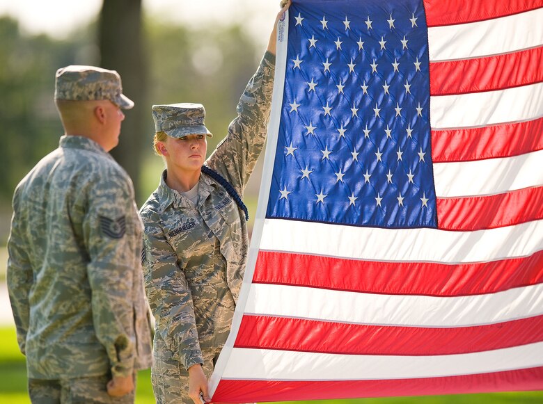 Staff Sgt. Jessica Nienhueser, right, a military training leader assigned to Detachment 3, 373rd Training Squadron, Dover Air Force Base, Del., prepares the American flag for folding during a retreat ceremony at the base flag pole Sept. 7, 2012, at Dover AFB. (U.S. Air Force photo by Roland Balik)
