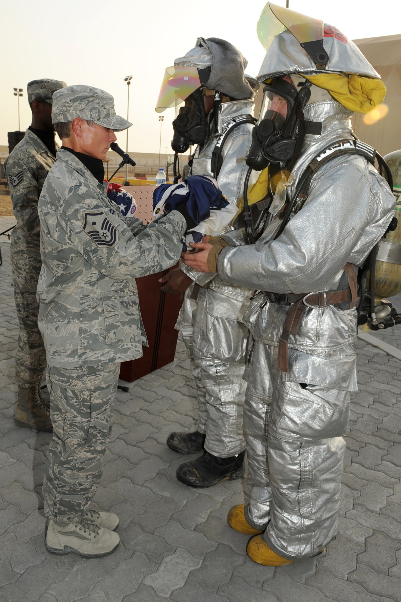 SOUTHWEST ASIA - U.S. Air Force Senior Airman Eloy Garcia, 380th Expeditionary Civil Engineer Squadron firefighter, hands the memorial 9/11 flag to Master Sgt. Laurie Cherry, 727th Expeditionary Air Control Squadron first sergeant, during a 9/11 memorial ceremony at the 380th Air Expeditionary Wing Sept. 11, 2012. The 380th Air Expeditionary Wing held a memorial to commemorate the 11th anniversary of this tragic day. (U.S. Air Force photo/Master Sgt. Scott MacKay)