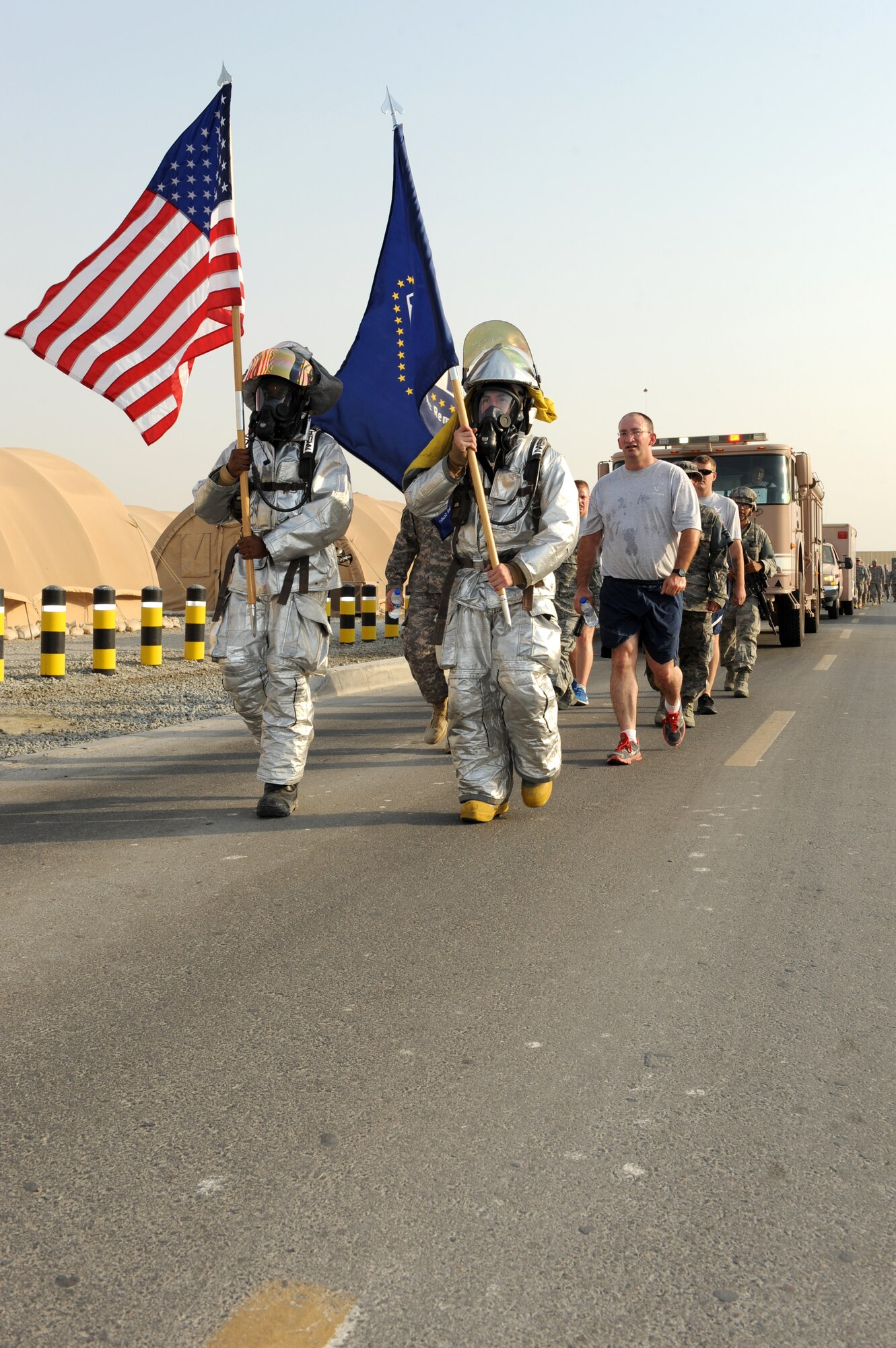 SOUTHWEST ASIA - U.S. Air Force Airman 1st Class Kendall Fair, left and Senior Airman Eloy Garcia, 380th Expeditionary Civil Engineer Squadron firefighters, lead members of the 380th Air Expeditionary Wing on the last lap around the base before a ceremony commemorating 9/11 Sept. 11, 2012. Members of the 380th AEW took turns marching the flags around the base for 12 hours before coming to rest at the 9/11 memorial site.  (U.S. Air Force photo/Master Sgt. Scott MacKay)
