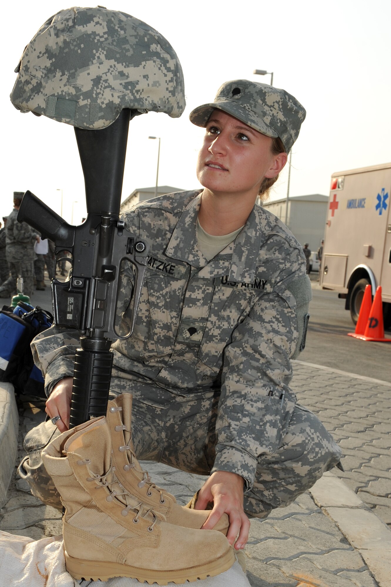 SOUTHWEST ASIA - U.S. Army Spc. Jennifer Patzke, 1st Battalion, 7th Air Defense Artillery Regiment solider, secures a pair of boots and a rifle during a 9/11 ceremony at the 380th Air Expeditionary Wing Sept. 11, 2012. The helmet, rifle and boots are placed to remember all the servicemen and women who have lost their lives in defense of our nation since the events of 9/11.  (U.S. Air Force photo/Master Sgt. Scott MacKay)
