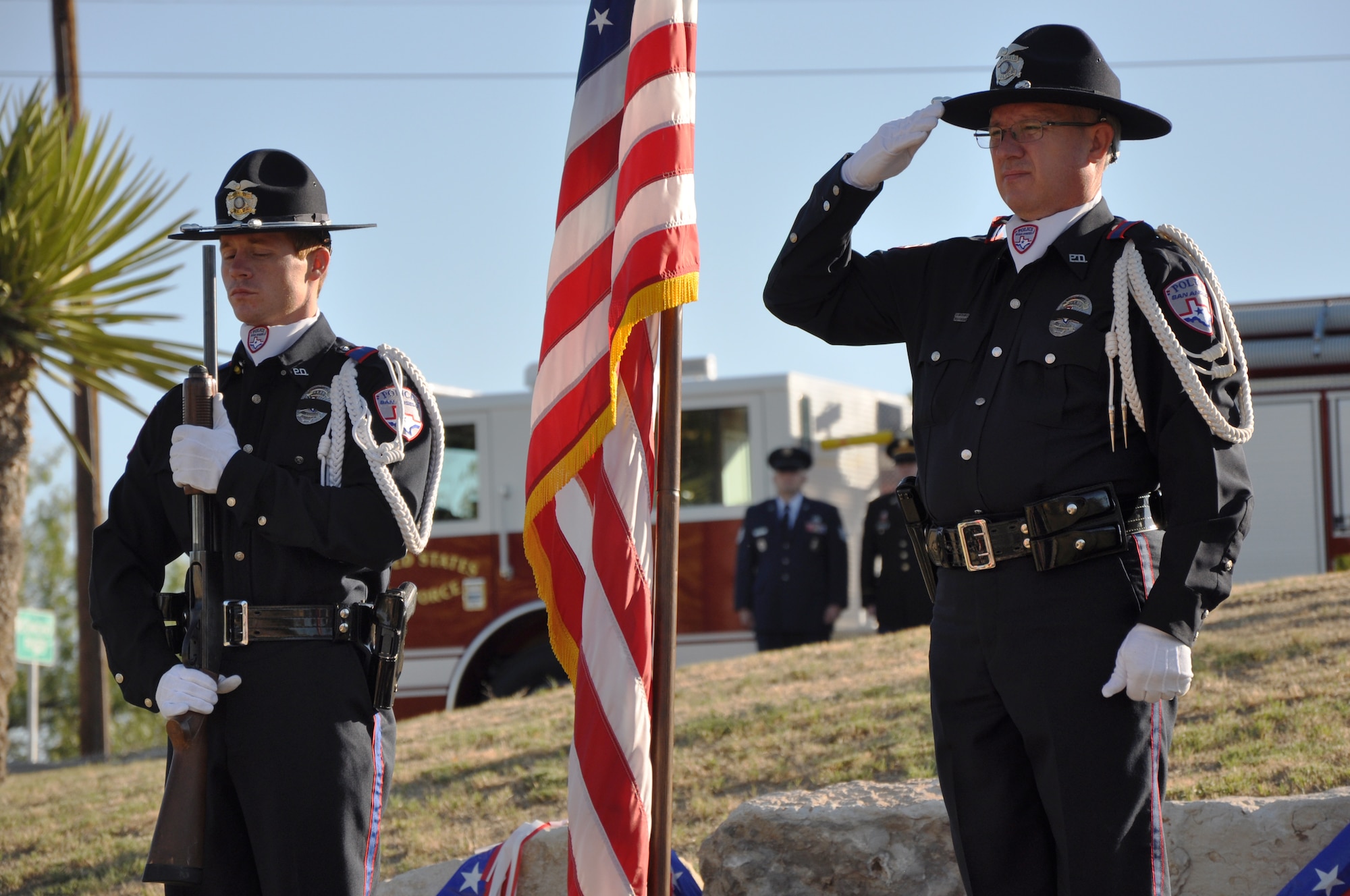 Steven Quade, San Angelo Police Department traffic investigator, salutes the flag while Detective Craig Thompson holds his weapon at attention as part of the color guard during the September 11th Ceremony outside the San Angelo Fine Arts Museum in San Angelo Sept. 11. The ceremony was held to honor the victims of the Sept. 11 tragedy, especially those who gave their own lives to rescue others. (Air Force Photo/ Staff Sgt. Tsuyoshi Shinzato)