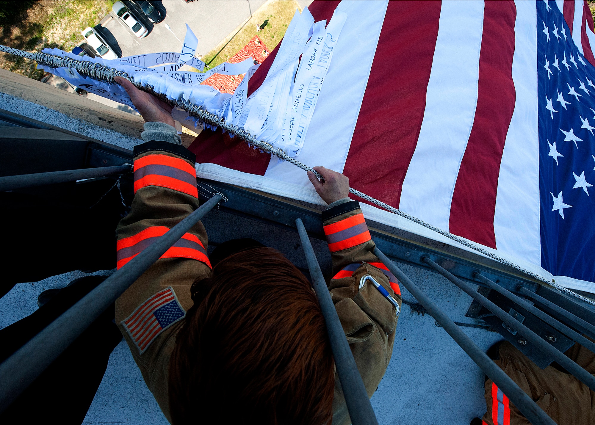 Amber Turek, a 96th Test Wing firefighter, adjusts ribbons over the balcony on either side of the flag. Fire department civilians and service members, ascended 11 stories carrying ribbons with the names of the 343 firefighters killed on Sept. 11, 2001. The event ended on top of the tower with participants hanging the ribbons over the balcony on either side of the American Flag. (U.S. Air Force photo/Randy Gon)
