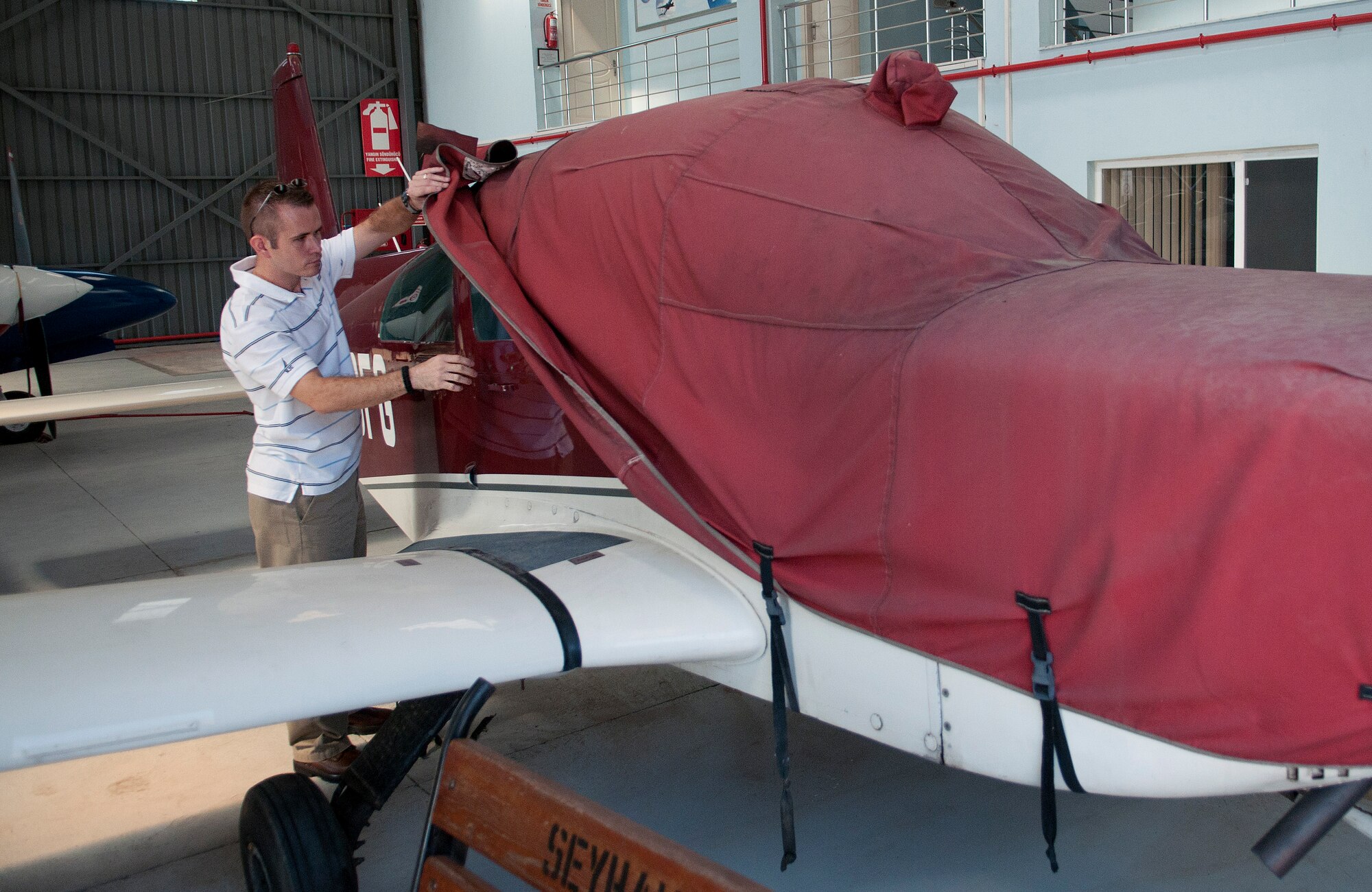 Capt. Ronald Bellue, 39th Operations Squadron, lifts the cover on a plane to look inside at the cockpit at a flight school Sept. 10, 2012, in Adana, Turkey. Members  of the 39th ABW visited the Adana airport and a flight school as part of an annual mid-air collision avoidance conference and to maintain their relationship with Turkish air traffic controllers. (U.S. Air Force photo by Senior Airman Daniel Phelps/Released)