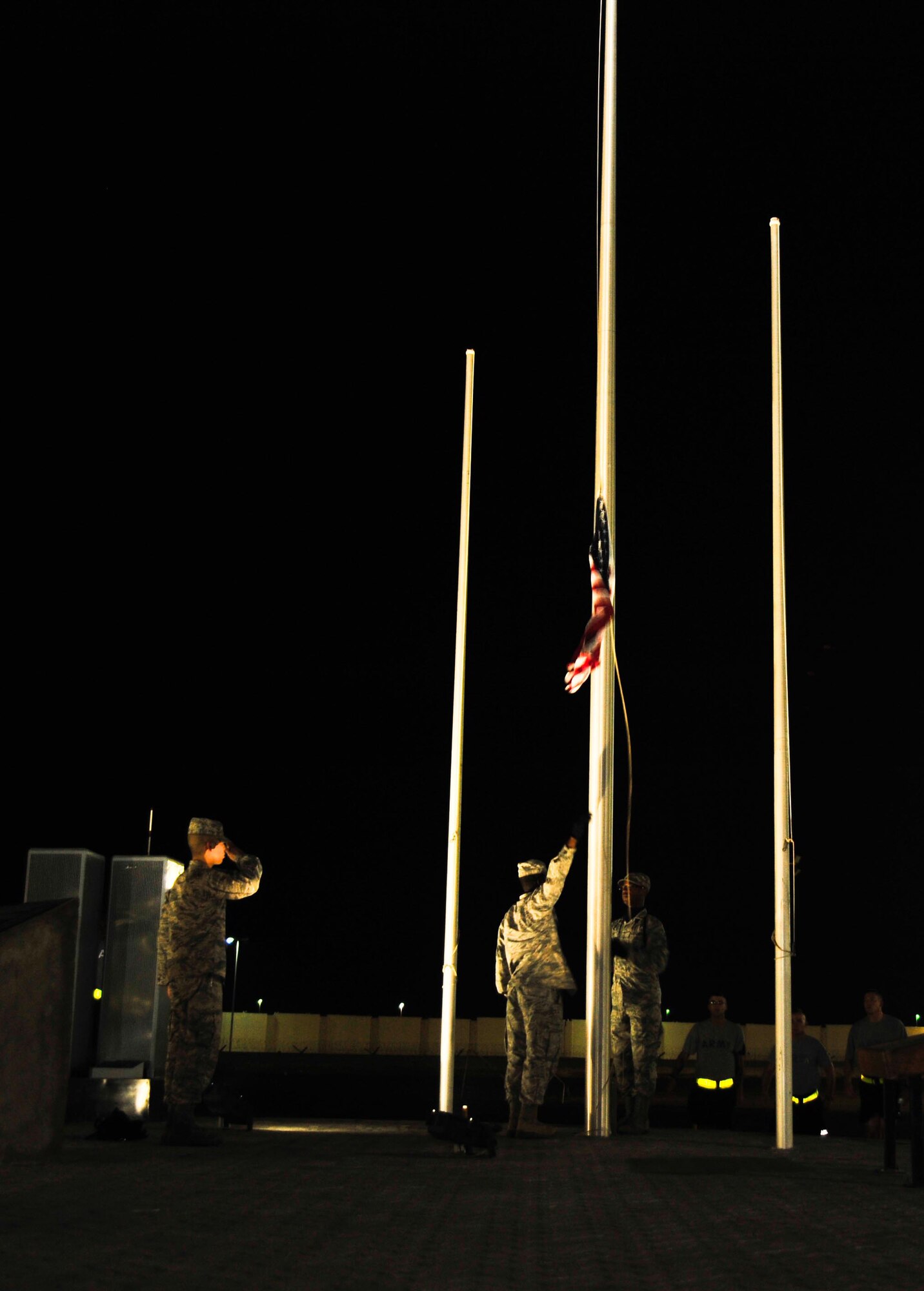 SOUTHWEST ASIA - U.S. Air Force Airmen from the 380th Air Expeditionary Wing bring the American flag to half-staff at the wing's 9/11 Memorial site Sept. 11, 2012. The wing honored the memory of the events of Sept. 11, 2001, with a 5-kilometer walk/run and 12-hour walk to remember that began and ended at the site. (U.S. Air Force photo/Tech. Sgt. Joshua Leach)