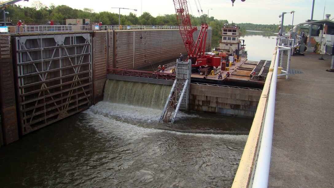 A crane lifts the stop logs, allowing water to fill the lock chamber following the removal and replacement of a pintal ball at Chouteau Lock and Dam 17 in Chouteau, Okla.