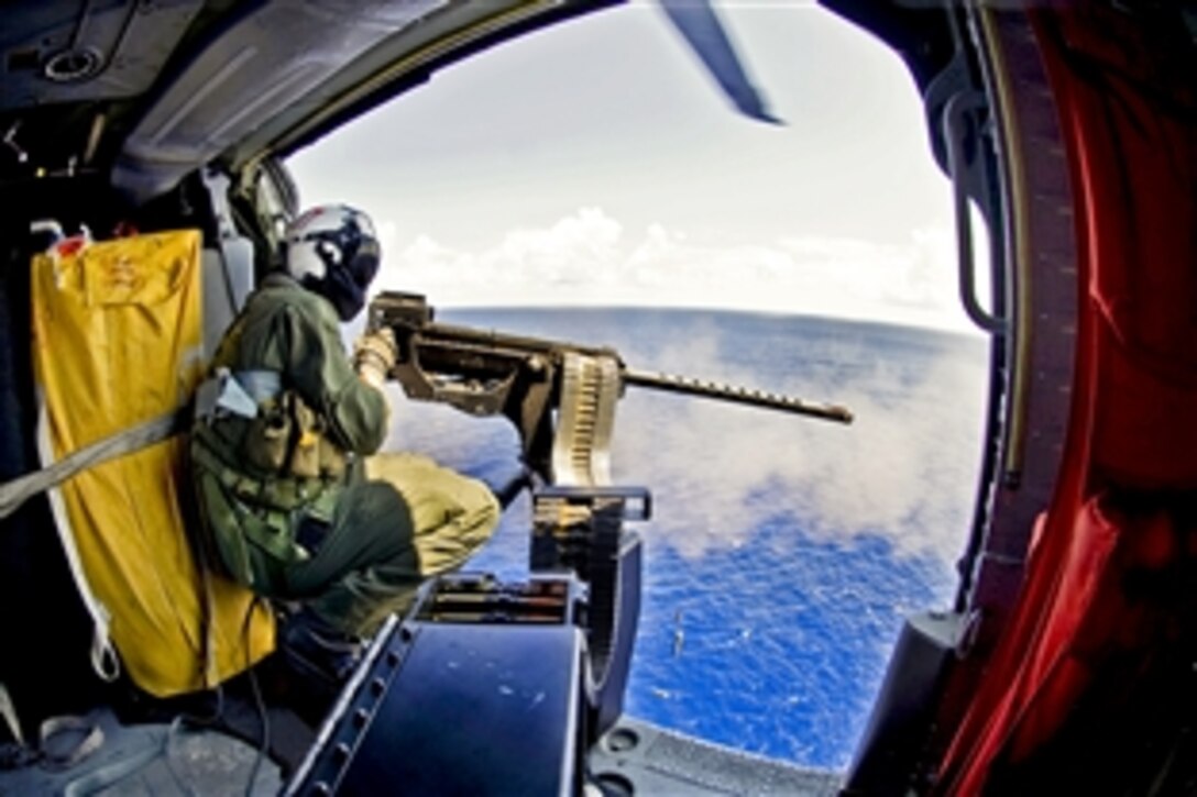 U.S. Navy Petty Officer 3rd Class Bobby Heimovitz, assigned to Helicopter Sea Combat Squadron 9, USS Harry S. Truman, fires a .50-caliber machine gun at a MK-25 smoke target in the Atlantic Ocean, Sept. 5, 2012. Heimovitz is a naval aircrewman helicopter. The squadron is under way with the aircraft carrier USS Harry S. Truman to support carrier qualifications.