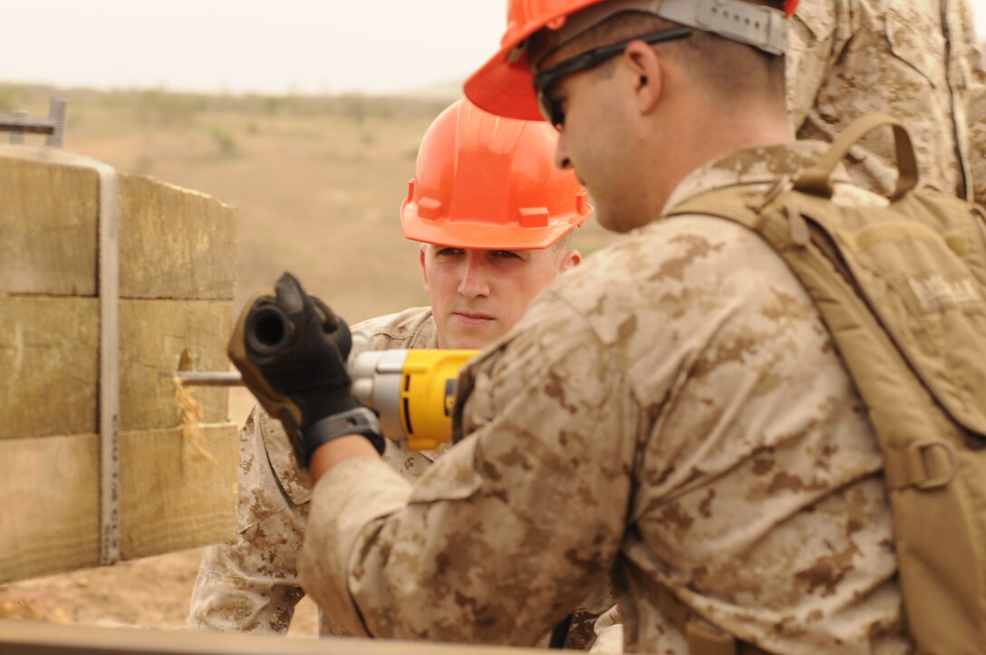 U.S. Marine Lance Cpl. Kevin Tye watches Lance Cpl. Zachary Ellis, both combat engineers with the Marine Wing Support Squadron 473, drill into a beam for a watchtower in Thiès, Senegal, July 11, 2012. Tye and Ellis are participating in Western Accord 2012, a multi-lateral exercise with Senegalese, several Western African nations and the Armed Forces of Burkina Faso, Guinea, Gambia and France.