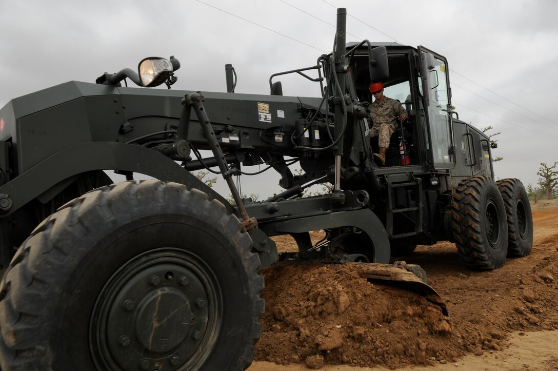 U.S. Marine Lance Cpl. Christopher Mitchoson, a combat engineer with the Marine Wing Support Squadron 473, grades a road to the new range in Thies, Senegal, July 11, 2012. Mitchoson is participating in Western Accord 2012, a multi-lateral exercise with Senegalese, several Western African nations and the Armed Forces of Burkina Faso, Guinea, Gambia and France.