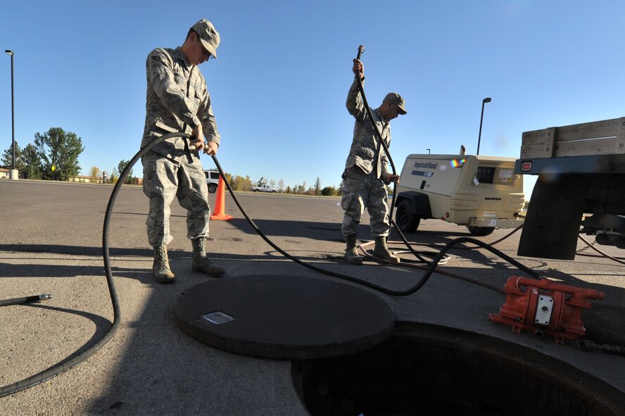 MINOT AIR FORCE BASE, N.D. -- Senior Airman Sixto Trevino and Airman 1st Class Wilson Arocho, 5th Civil Engineer Squadron water and fuel systems maintainers, prepare their equipment to perform maintenance on a fuel tank here, Sept. 12. Keeping the water level down is a recurring maintenance job that keeps the fuel system running correctly. (U.S. Air Force photo/Senior Airman Brittany Y. Auld)