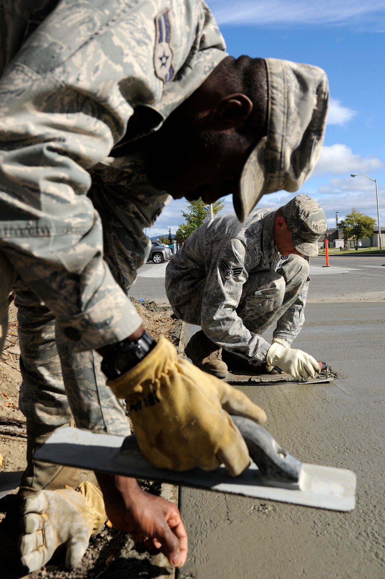 U.S. Air Force Senior Airman Ryan Halter and Airman 1st Class Devoris Weldon, 354th Civil Engineer Squadron pavement equipment operators, use trowels to pave wet concrete Sept. 10, 2012, Eielson Air Force Base, Alaska. Once completed, joints will be added to prevent cracks on the new sidewalk. (U.S. Air Force photo/ Staff Sgt. Jim Araos)