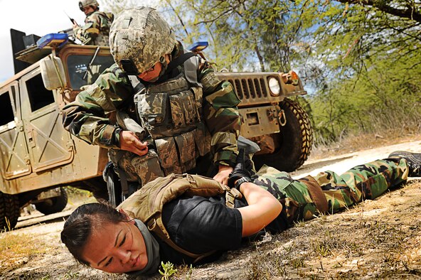 Airman 1st Class Lucia Leija places handcuffs on Staff Sgt. Kristen Cruz, both 647th Security Forces, during  an Operational Readiness Exercise on Joint Base Pearl Harbor-Hickam, Hawaii, Sept. 12. The exercise scenario involved a vehicle ambush and a personnel recovery mission. (U.S. Air Force photo/Senior Airman Lauren Main)