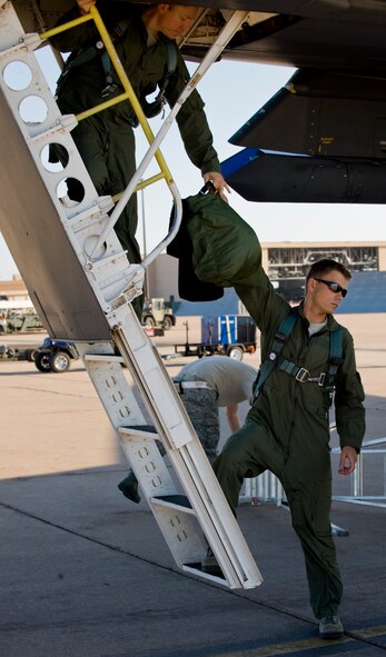 U.S. Air Force Capt. Artur Kosycarz, right, 337th Test and Evaluation Squadron, hands Maj. Thomas Bryant, 337th TES, his gear prior to boarding a B-1 Bomber Sept. 7, 2012, at Dyess Air Force Base Texas. The 337th TES is one of four Dyess squadrons competing in the Global Strike Challenge. (U.S. photo by Airman 1st Class Charles V. Rivezzo/Released) 
