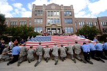 MINOT, N.D. -- Airmen from Minot Air Force Base joined members of the Minot community including local firefighters in the unfurling of the National 9/11 flag at Minot State University, Sept. 6. Destroyed in the attack and stitched back together by disaster survivors, the National 9/11 flag contains pieces of retired American flags from all 50 states and exemplifies the American people's resilience. (U.S. Air Force photo/Senior Airman Jesse Lopez)