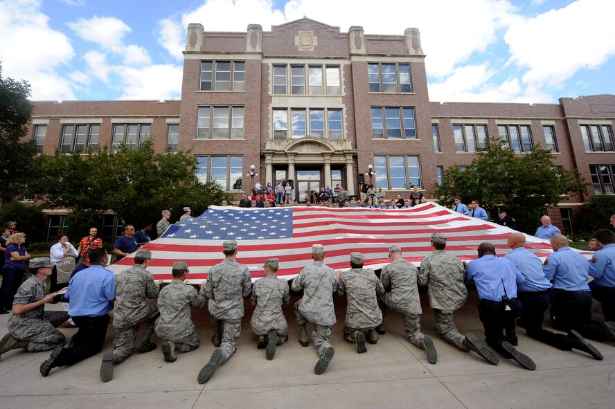 MINOT, N.D. -- Airmen from Minot Air Force Base joined members of the Minot community including local firefighters in the unfurling of the National 9/11 flag at Minot State University, Sept. 6. Destroyed in the attack and stitched back together by disaster survivors, the National 9/11 flag contains pieces of retired American flags from all 50 states and exemplifies the American people's resilience. (U.S. Air Force photo/Senior Airman Jesse Lopez)