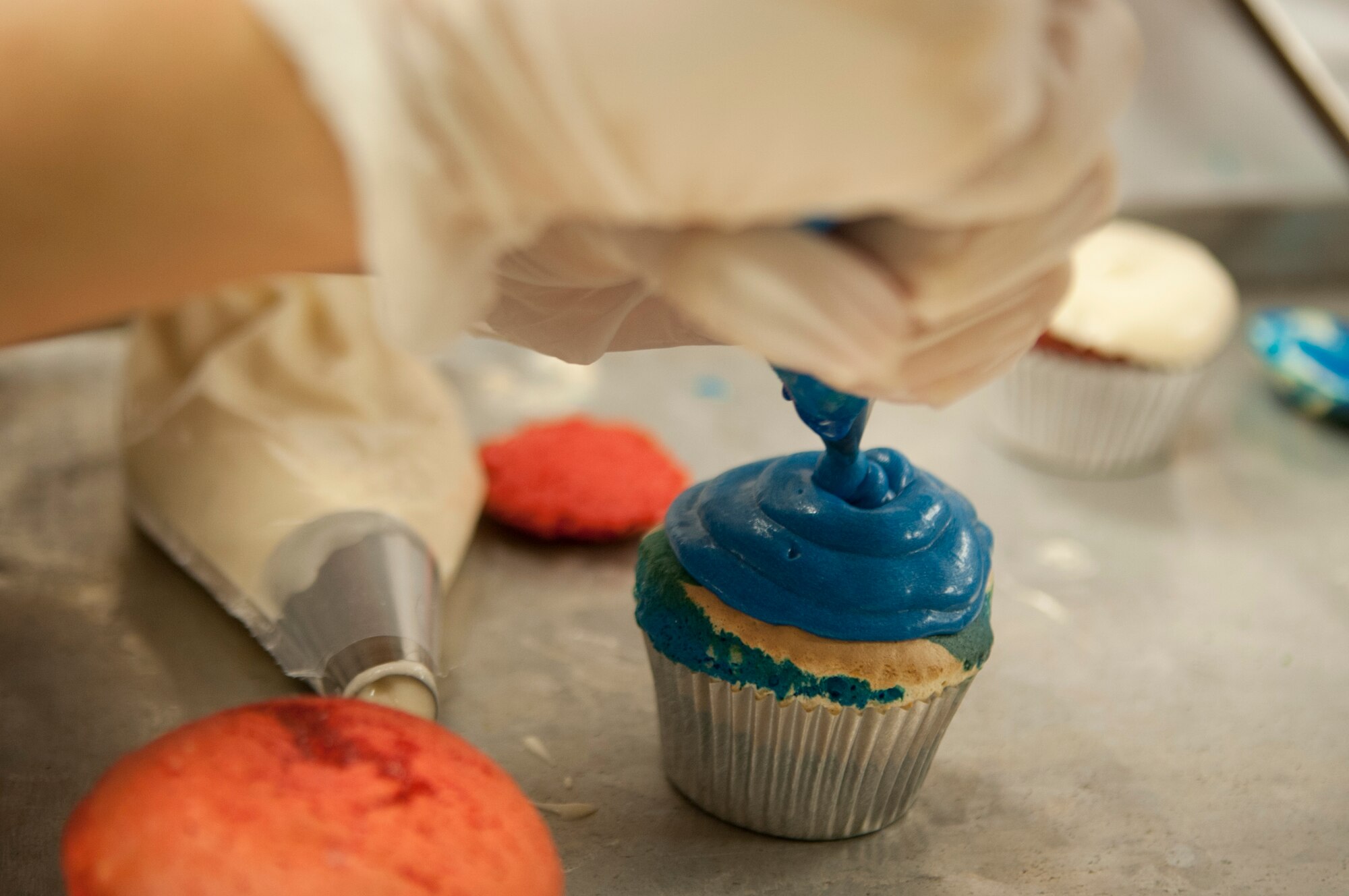 A competitor decorates a cupcake for Moody’s Cupcake Wars competition at Moody Air Force Base, Ga., Aug. 28, 2012. Each team had to make three styles of cupcakes in the theme of the Air Force’s 65th birthday and had to contain the secret ingredient of soft drinks. (U.S. Air Force photo by Airman 1st Class Paul Francis/Released)
