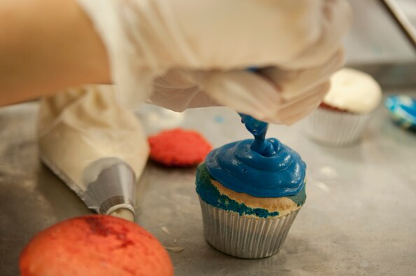 A competitor decorates a cupcake for Moody’s Cupcake Wars competition at Moody Air Force Base, Ga., Aug. 28, 2012. Each team had to make three styles of cupcakes in the theme of the Air Force’s 65th birthday and had to contain the secret ingredient of soft drinks. (U.S. Air Force photo by Airman 1st Class Paul Francis/Released)
