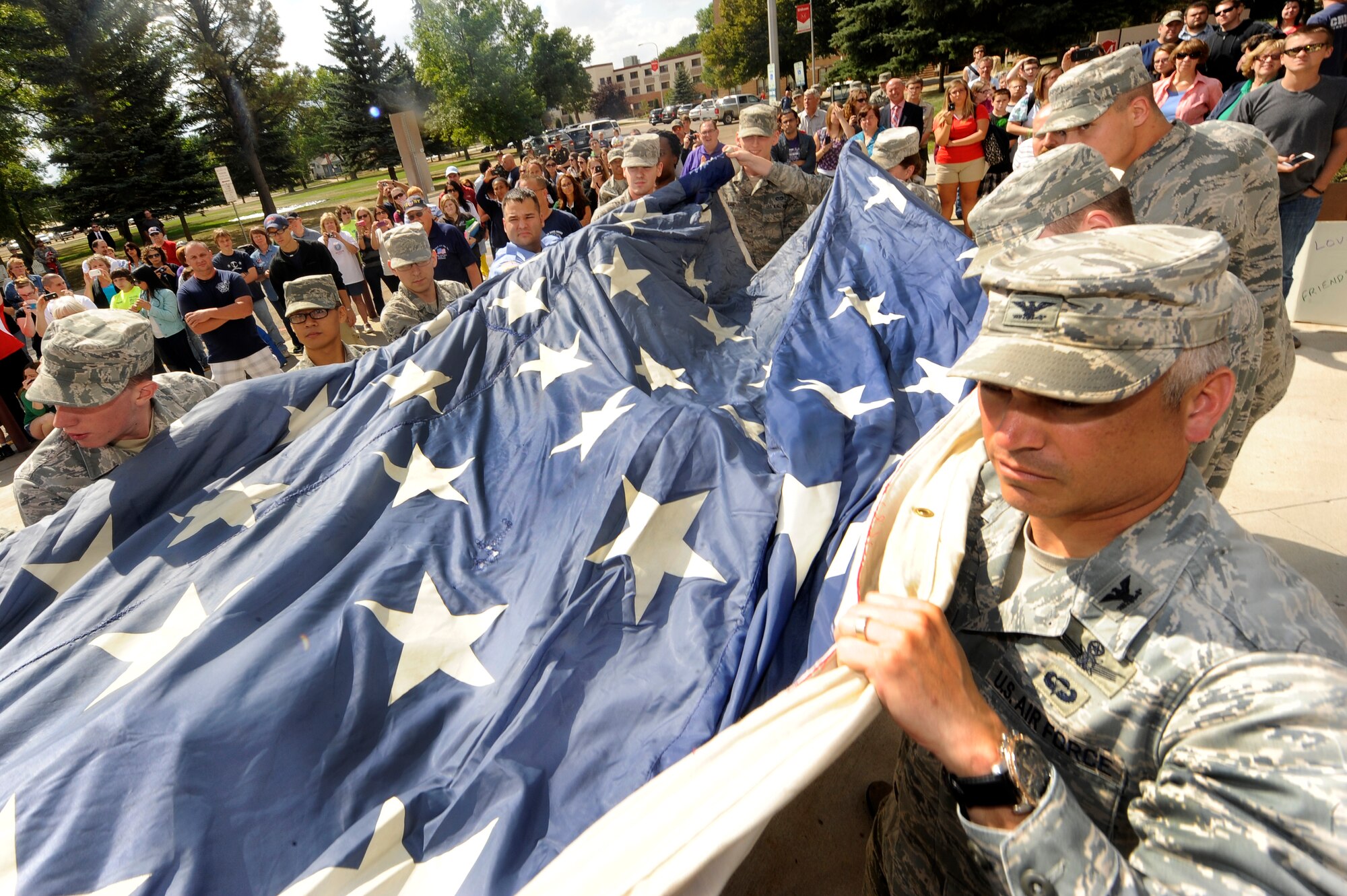 MINOT, N.D. -- Airmen from Minot Air Force Base joined members of the Minot community including local firefighters in the unfurling of the National 9/11 flag at Minot State University, Sept. 6. Destroyed in the attack and stitched back together by disaster survivors, the National 9/11 flag contains pieces of retired American flags from all 50 states and exemplifies the American people's resilience. (U.S. Air Force photo/Senior Airman Jesse Lopez)
