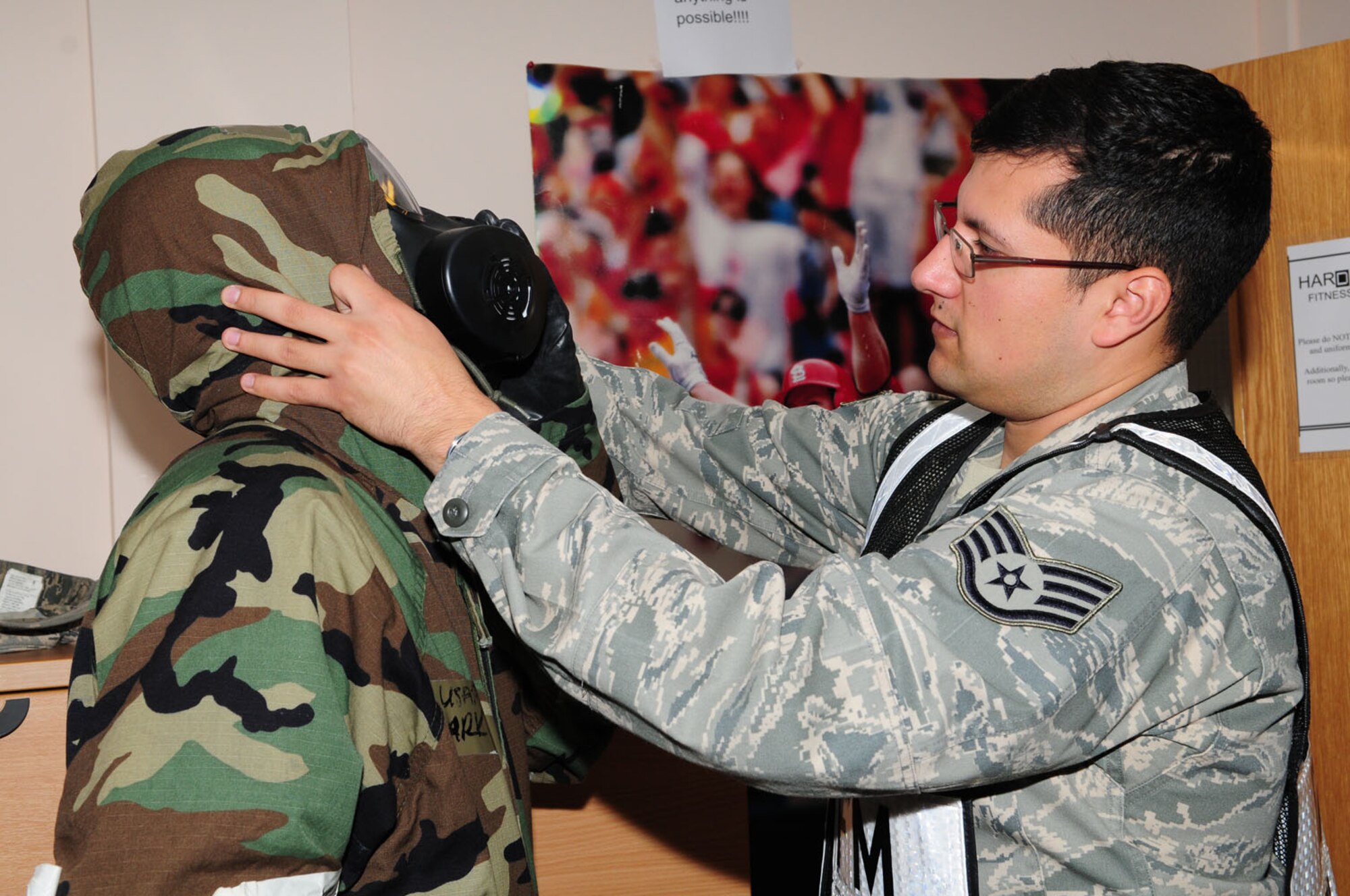RAF MILDENHALL, England – Right, Staff Sgt. David Rodriguez, exercise evaluation team member and 100th Air Refueling Wing plans and programs, evaluates the fit of an Airman’s gas mask and corrects the mask seal during an operational readiness exercise Sept. 12, 2012, at the Hardstand Fitness Center. (U.S. Air Force photo/Karen Abeyasekere)