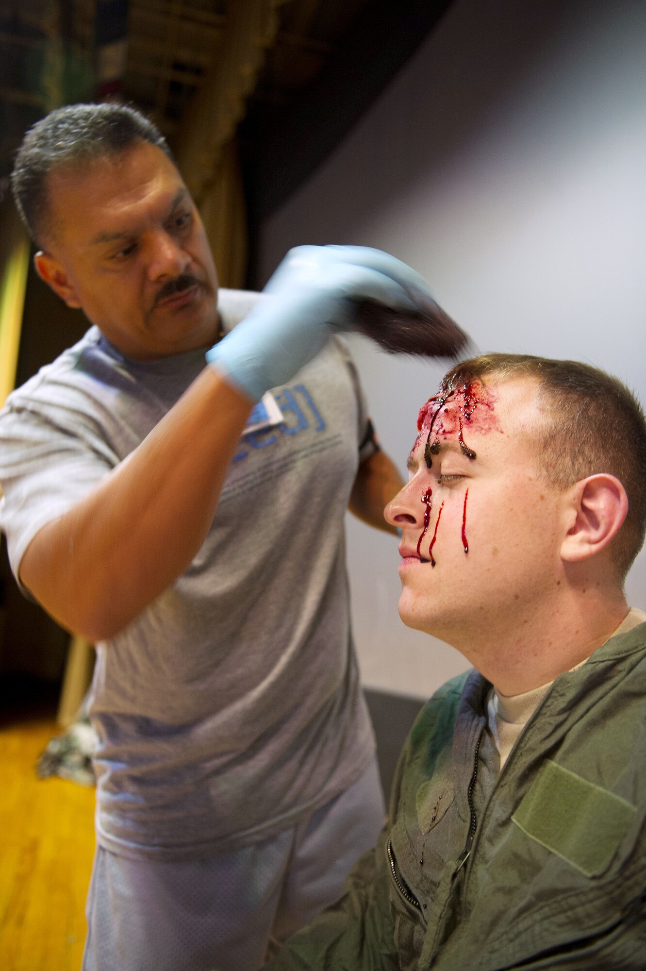 YOKOTA AIR BASE, Japan – Chief Master Sgt. Rojelio Martinez, 374th Medical Group exercise evaluator, applies moulage makeup to the forehead of Cpl. Joseph Sammons, a role player for an emergency management exercise at Yokota Air Base, Japan on Sept. 13, 2012. The makeup allows the exercise evaluation team to create the appearance of injuries on the role players to heighten the sense of realism during the exercise (U.S. Air Force photo by Staff Sgt. Chad C. Strohmeyer)