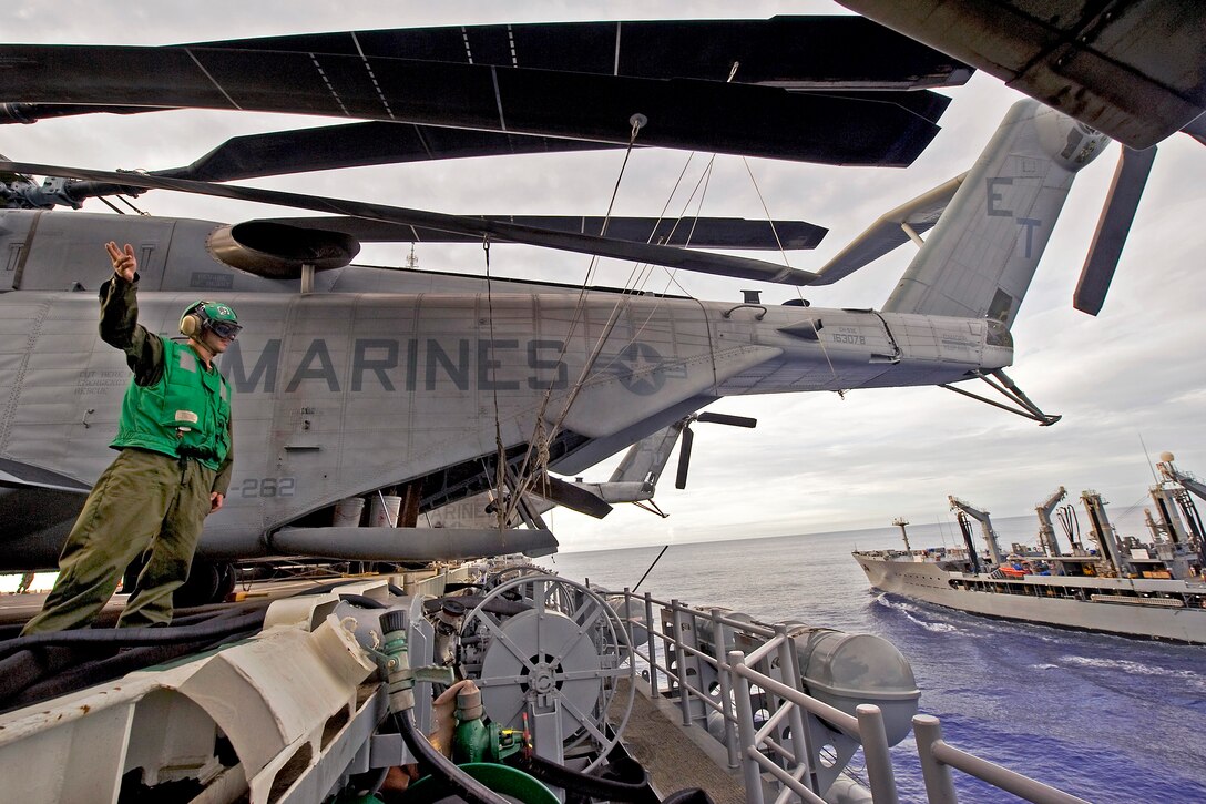 U.S. Marine Corps Cpl. James Cutler waves to the Military Sealift Command fleet replenishment oiler USNS John Ericsson after a replenishment at sea aboard the amphibious assault ship USS Bonhomme Richard under way in the Philippine Sea, Sept. 9, 2012. Cutler is assigned to Marine Medium Helicopter Squadron 262.